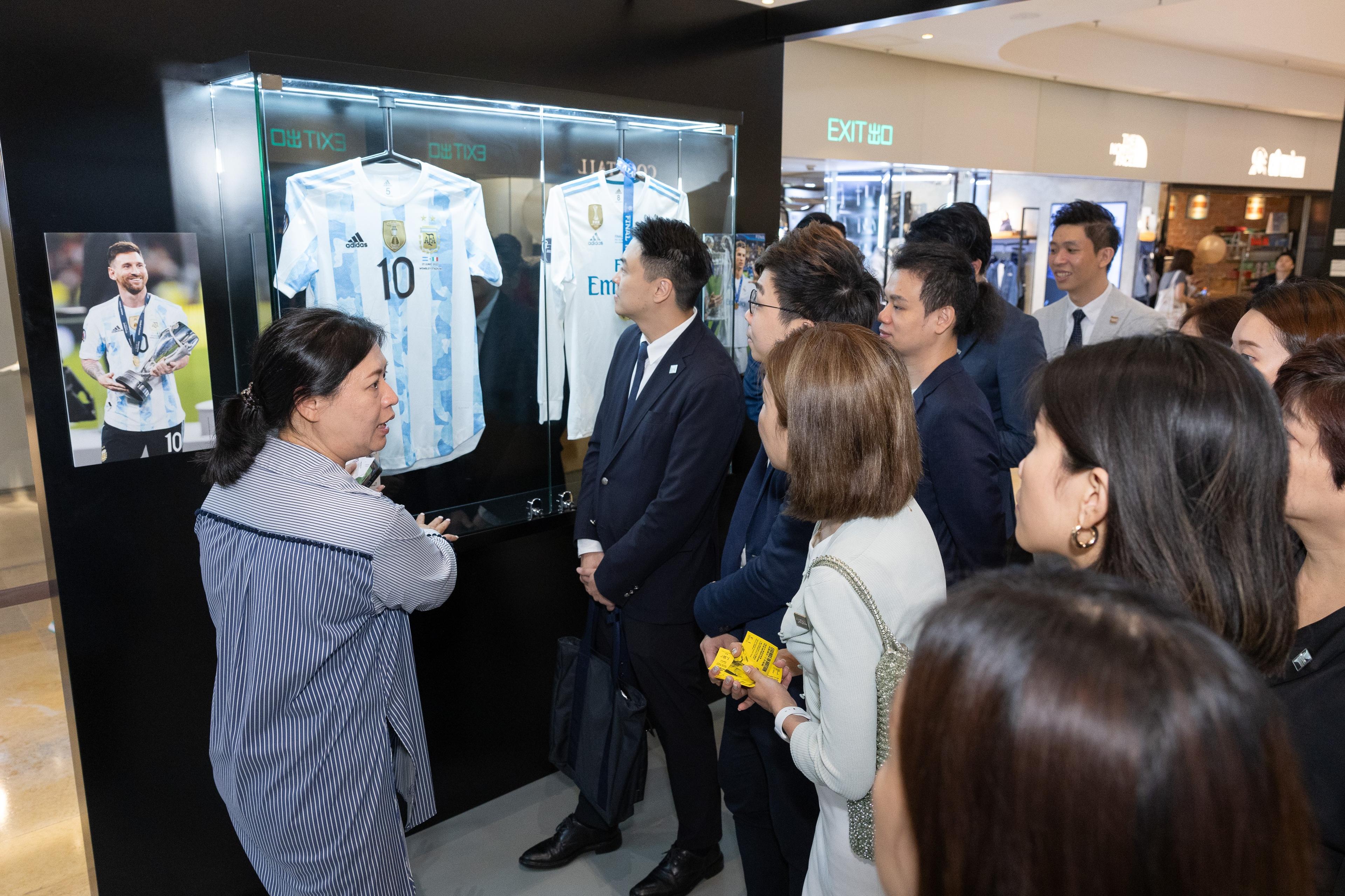 a group of people are standing around a display case with jerseys on it .
