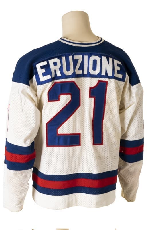Back of a white hockey jersey with blue shoulders, "ERUZIONE" and "21" in blue and red.