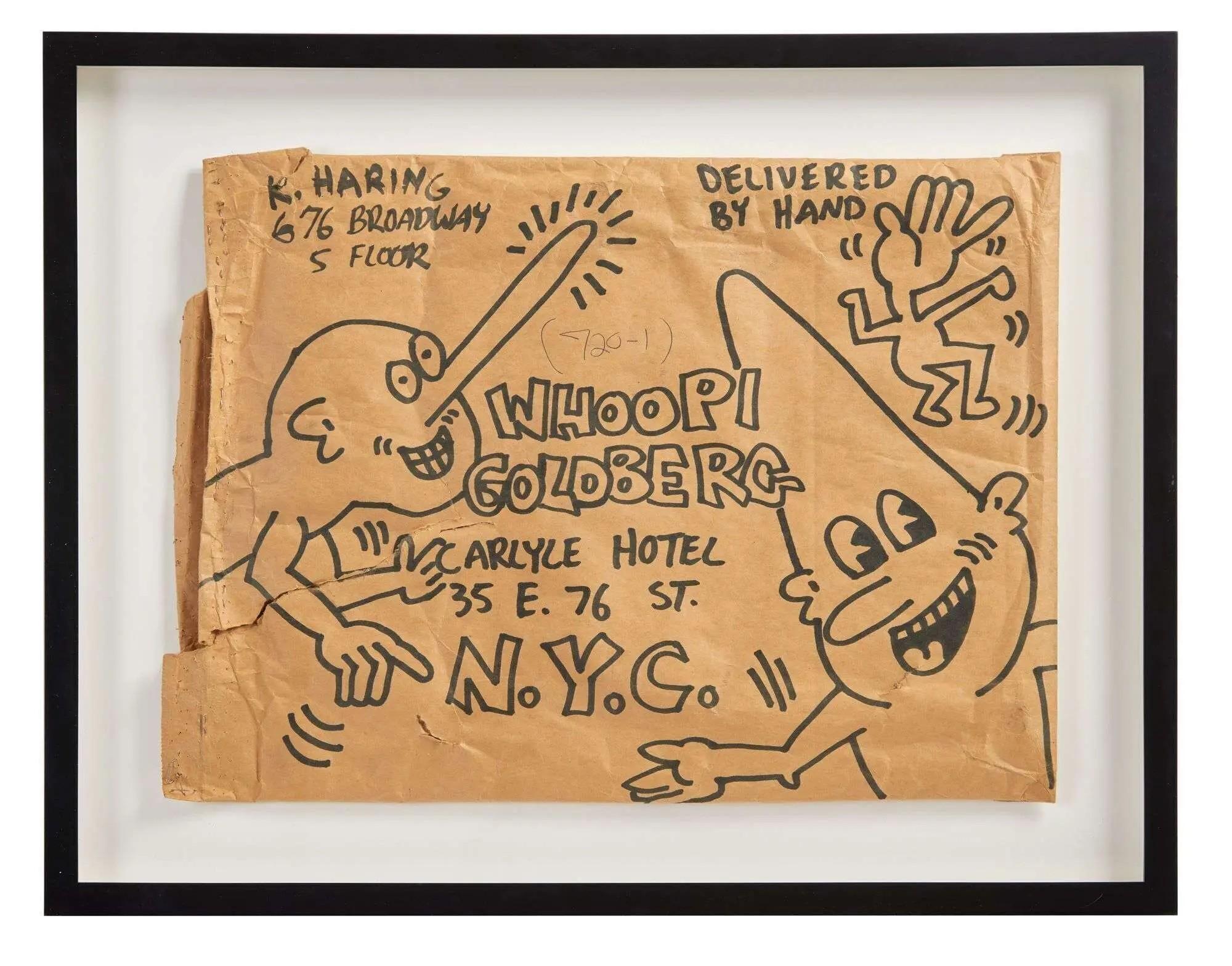 Framed Keith Haring drawing on a brown paper envelope addressed to Whoopi Goldberg, with smiling cartoon figures.