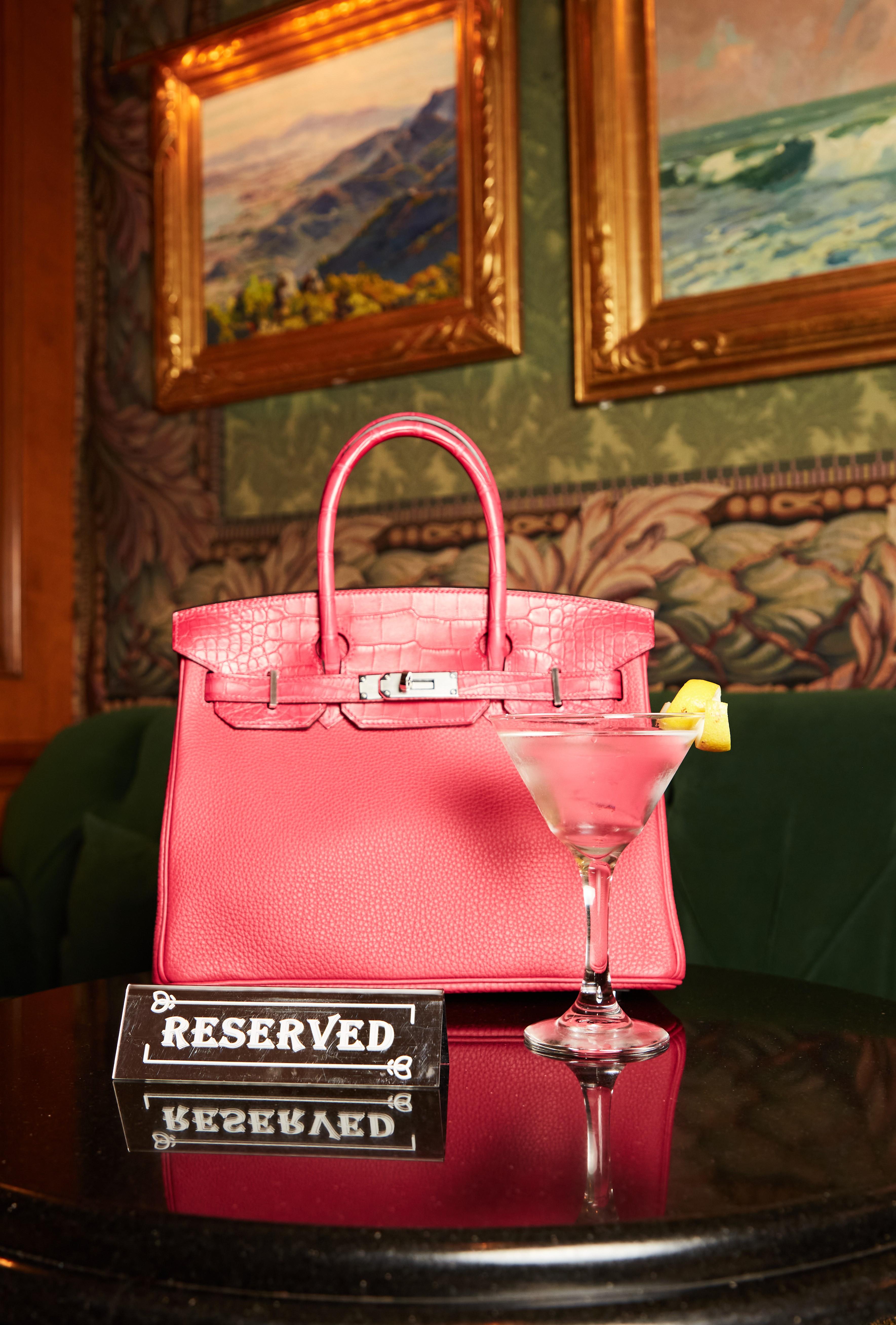 a reserved sign next to a pink purse and a martini