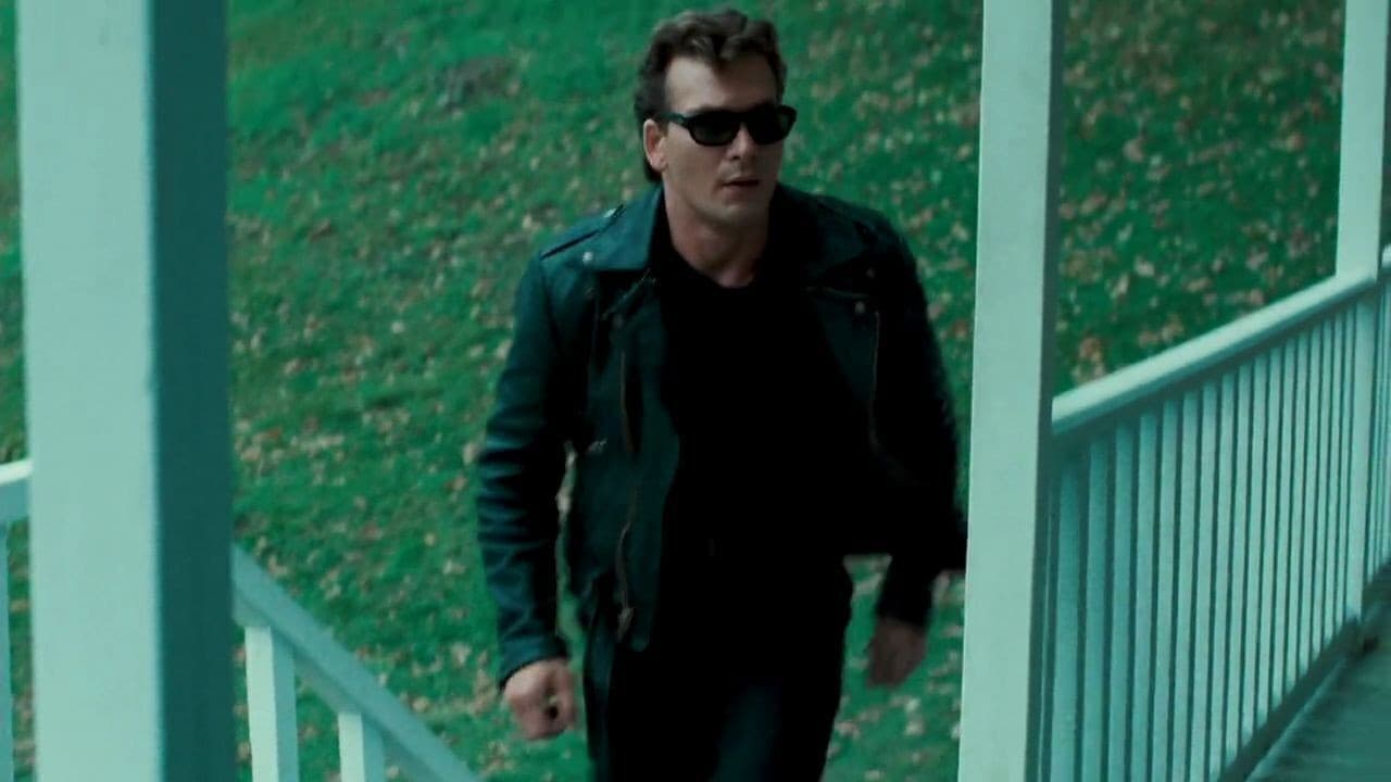 a man wearing sunglasses and a leather jacket is walking down a porch .
