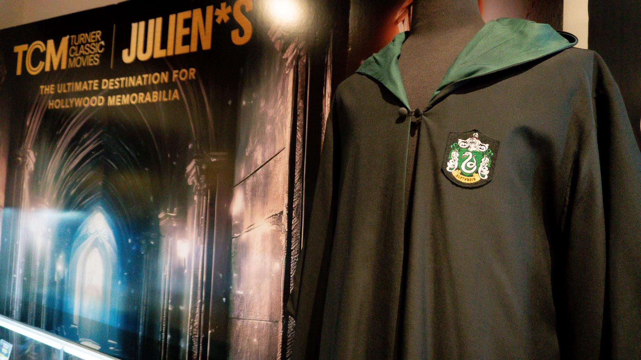a slytherin robe is hanging on a mannequin in front of a poster .