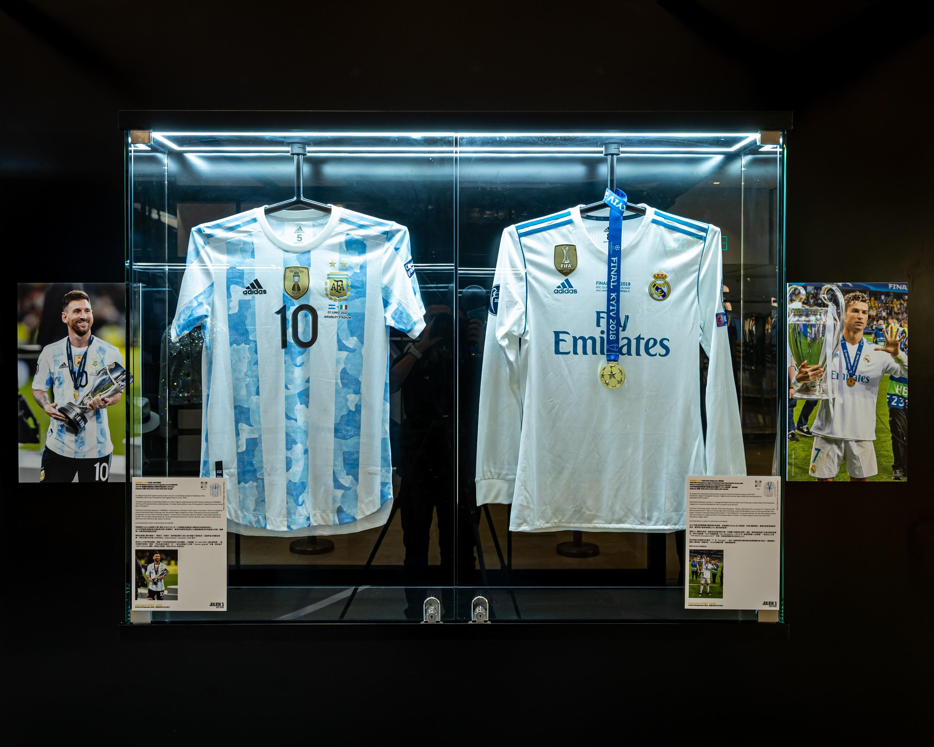 two soccer jerseys are displayed in a glass case .