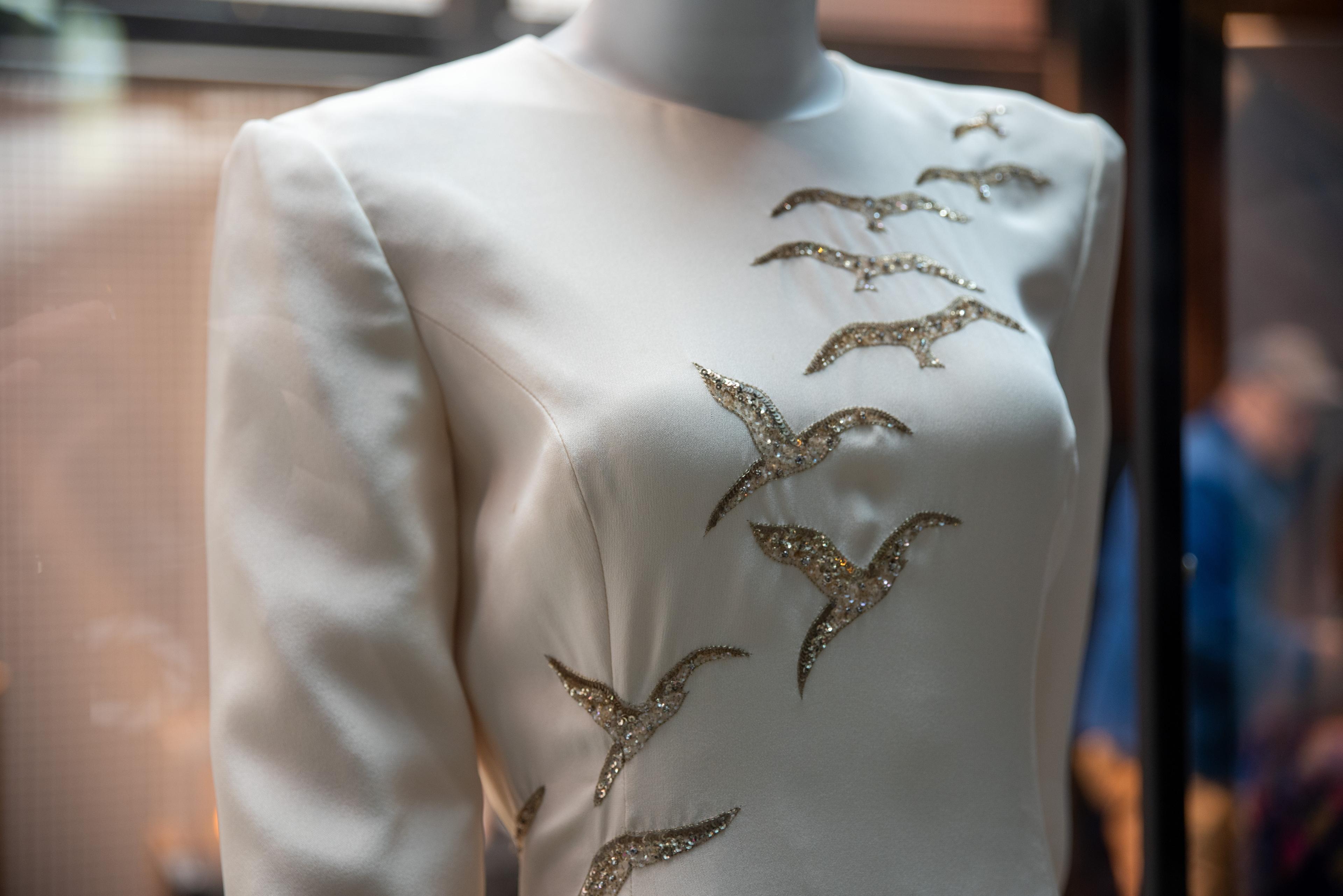 a close up of a white dress with embellished birds on it