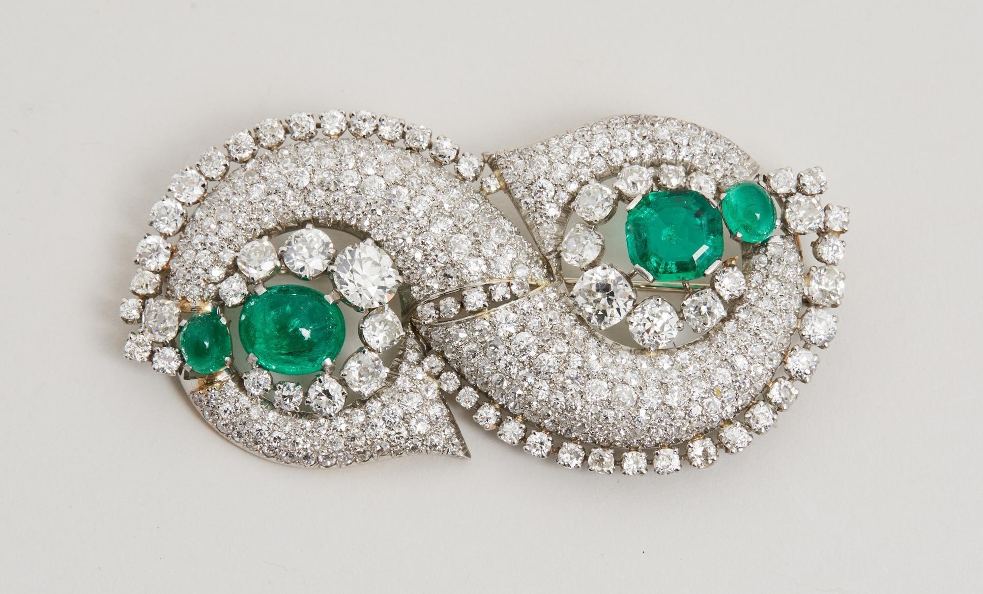Lot #36. Elizabeth Taylor | Art Deco Emerald and Diamond Brooch, Circa 1935 a brooch with emeralds and diamonds on a white surface .