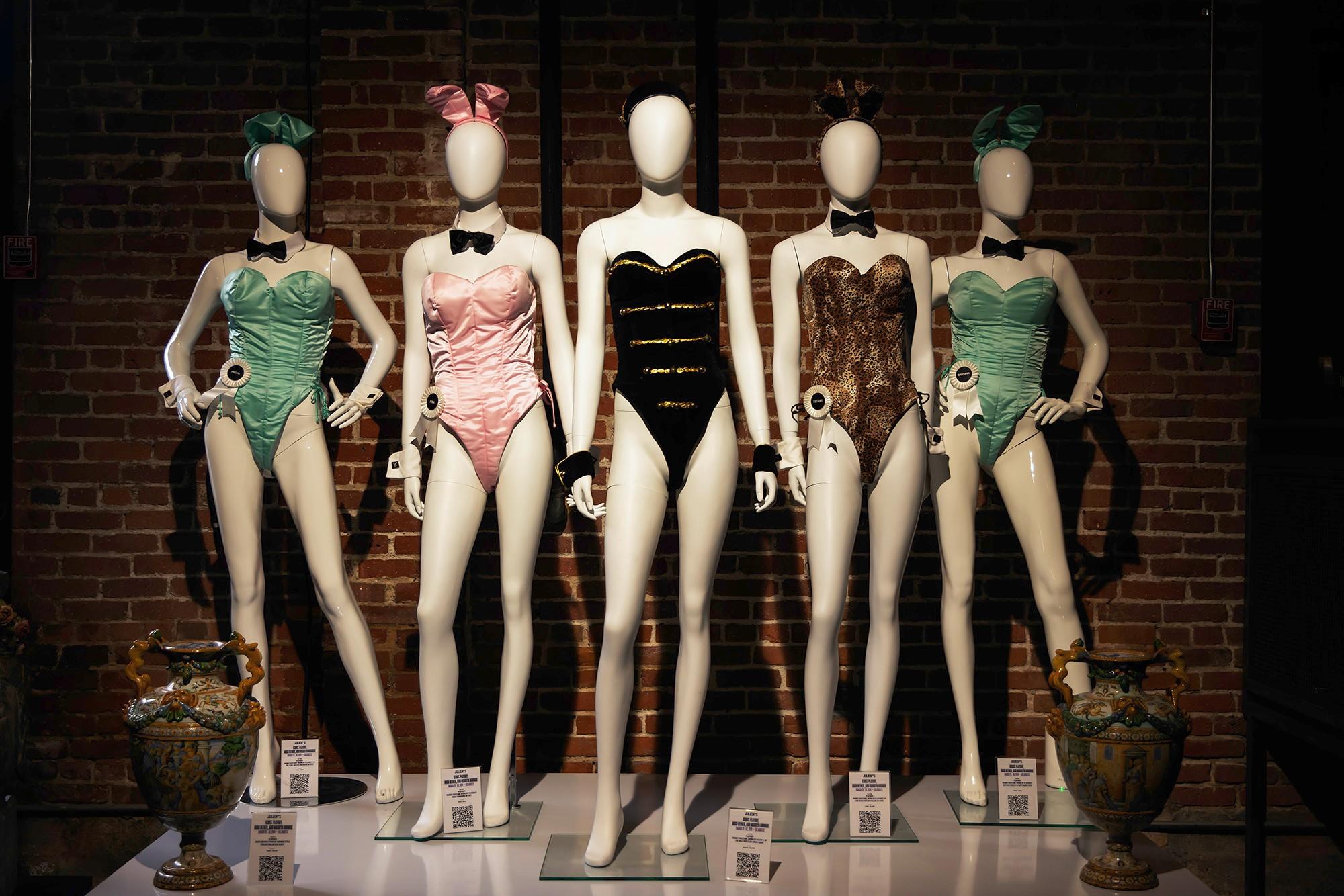 a group of mannequins are standing next to each other in front of a brick wall .