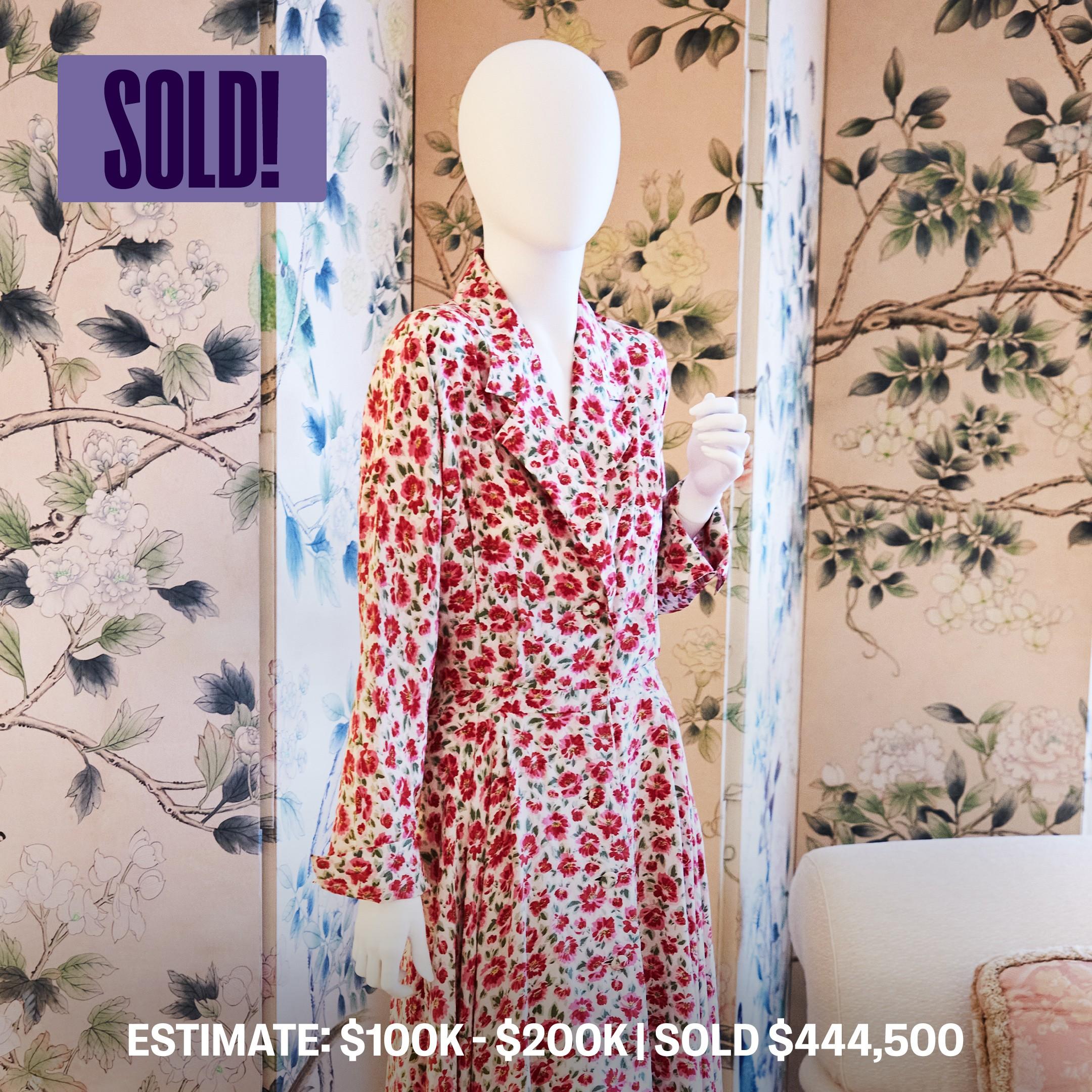 a mannequin wearing a red and white floral dress is standing in front of a sold sign