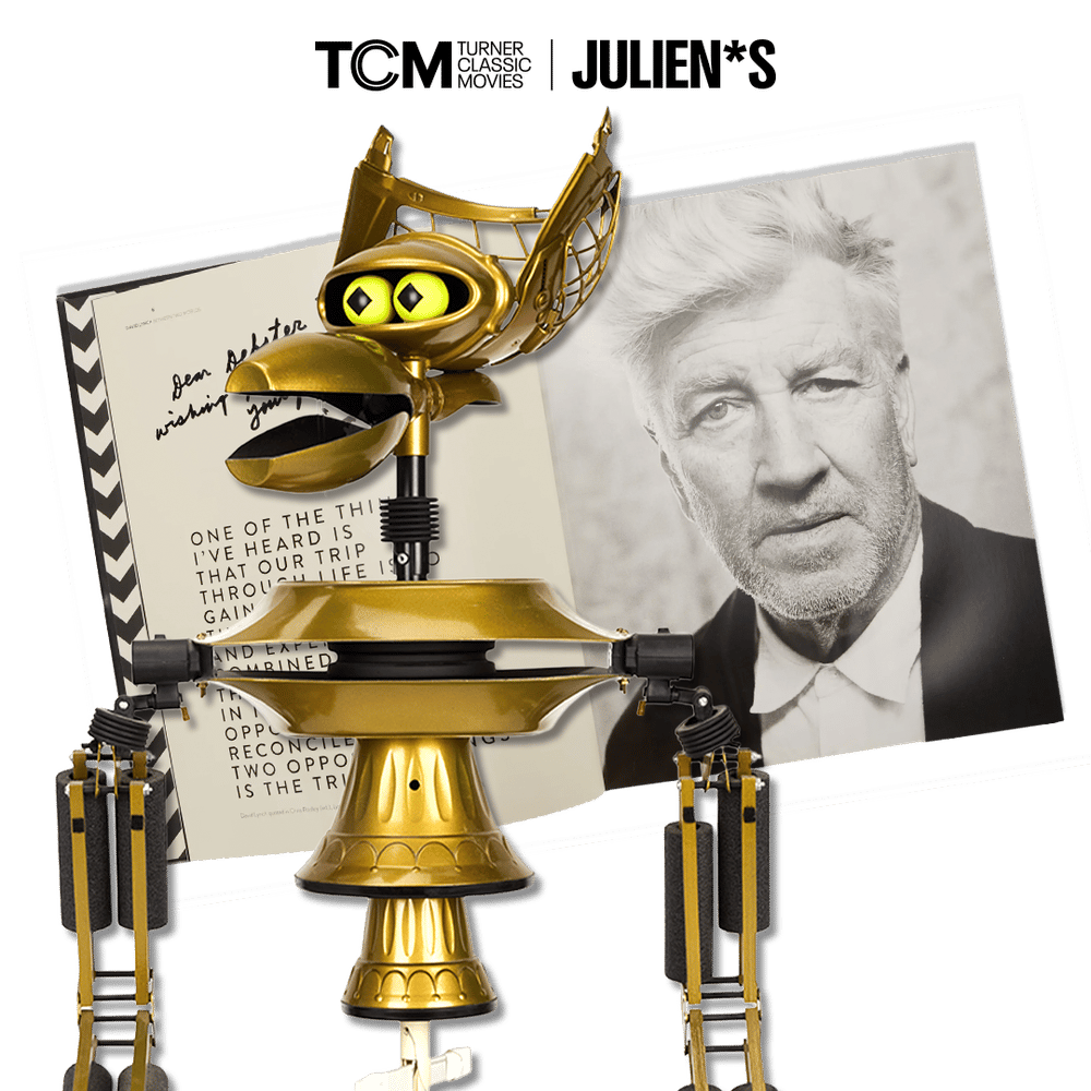 Crow T. Robot, a golden bird-like robot, holds a script for David Lynch's Lost Highway featuring a man's black and white photo.