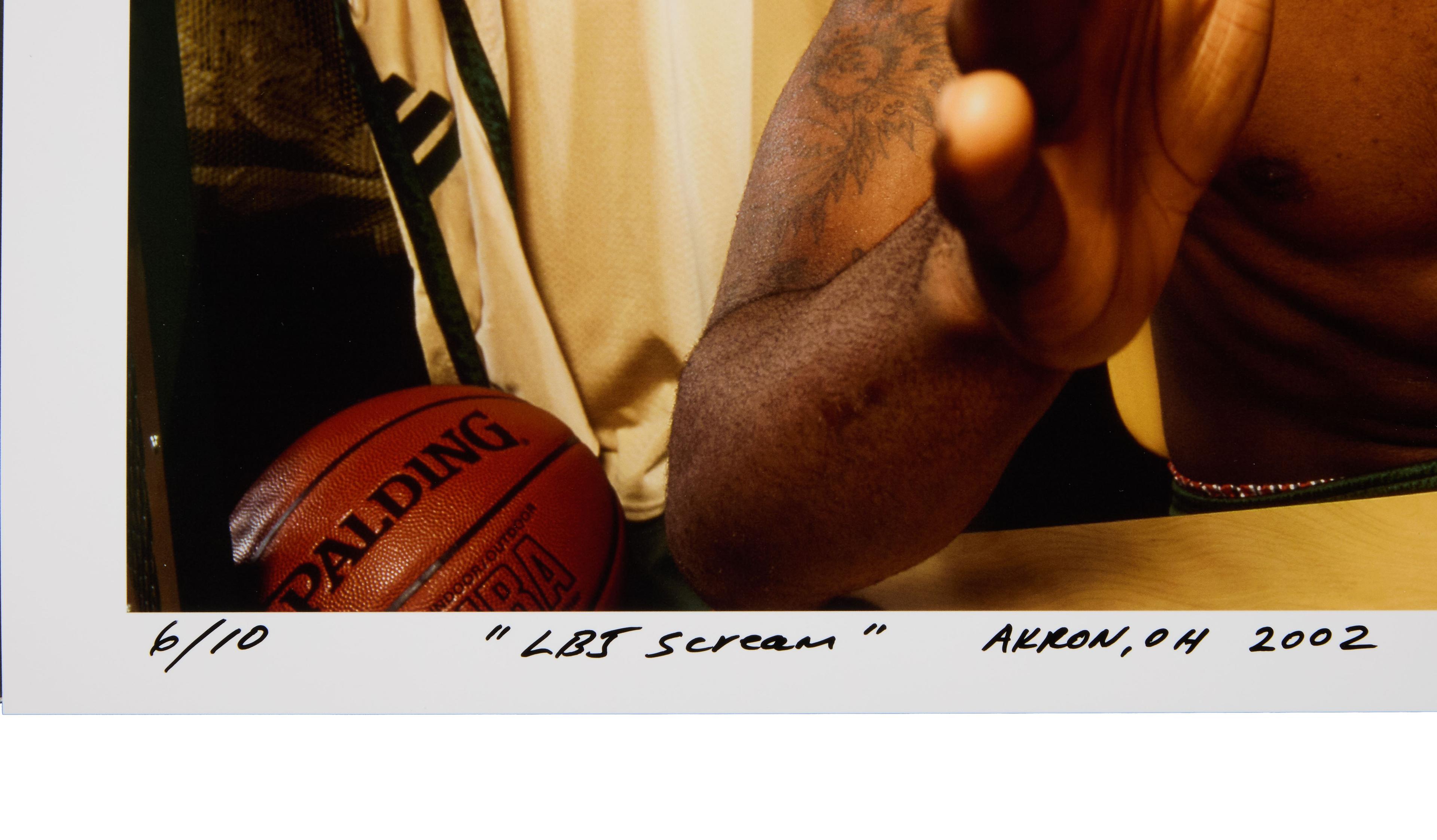 a man with a tattoo on his arm is sitting next to a basketball .