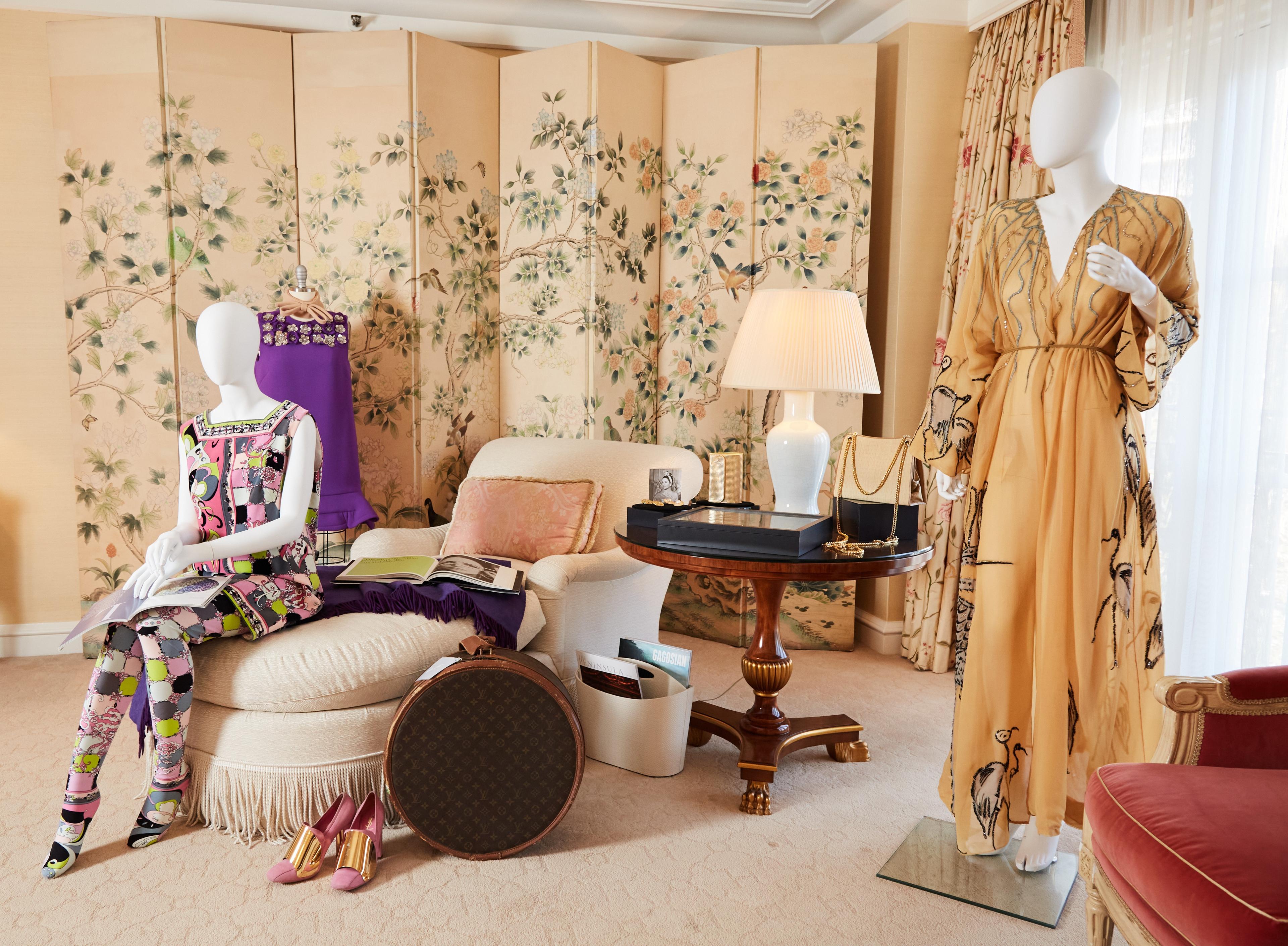 a living room with two mannequins sitting on a couch and a table .