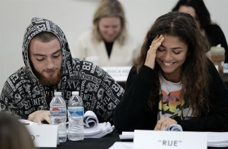 a man and a woman are sitting at a table reading a script .