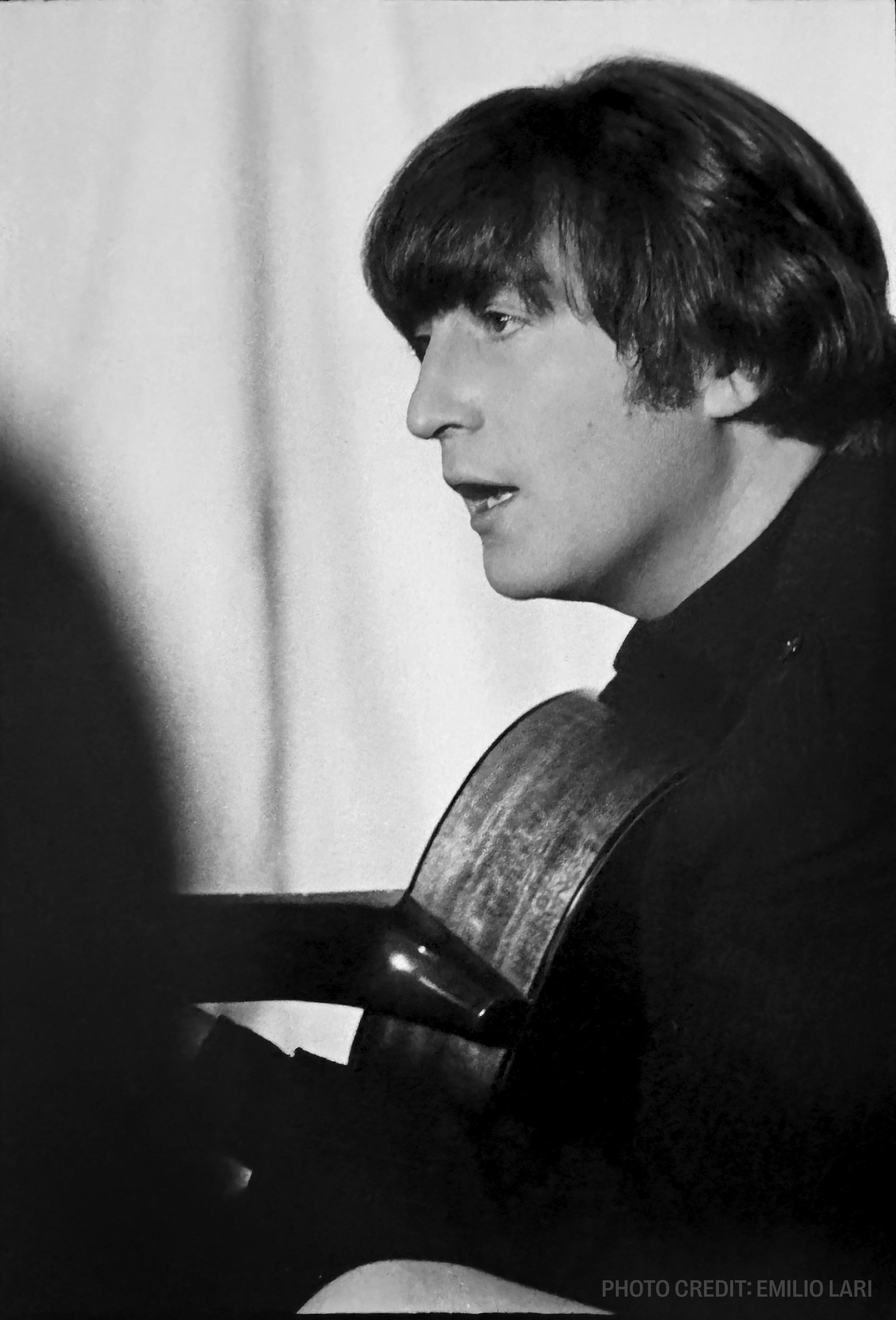 a black and white photo of john lennon playing a guitar