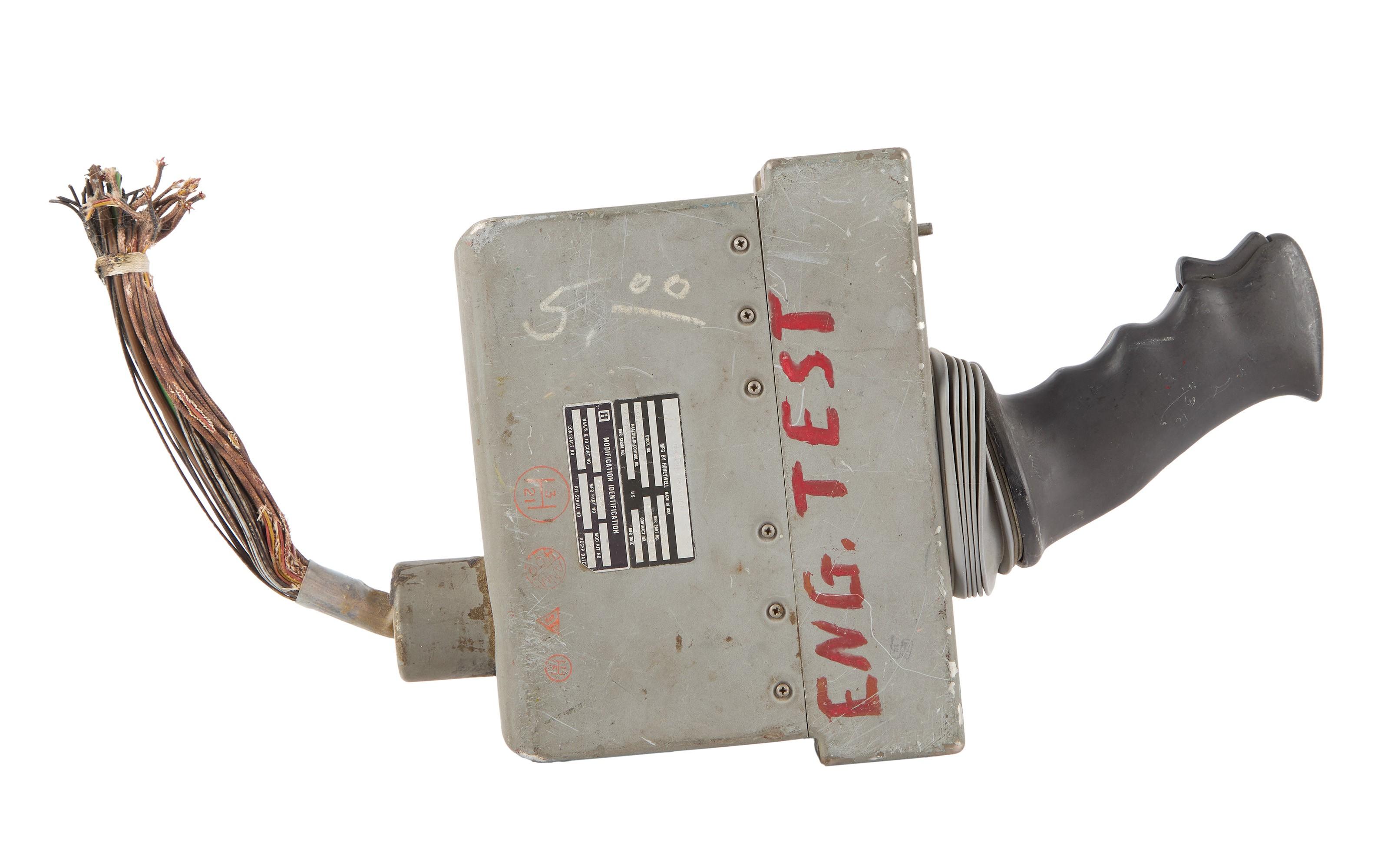 Grey control stick with a black ergonomic grip, exposed wires, and "ENG. TEST" in red on its side.