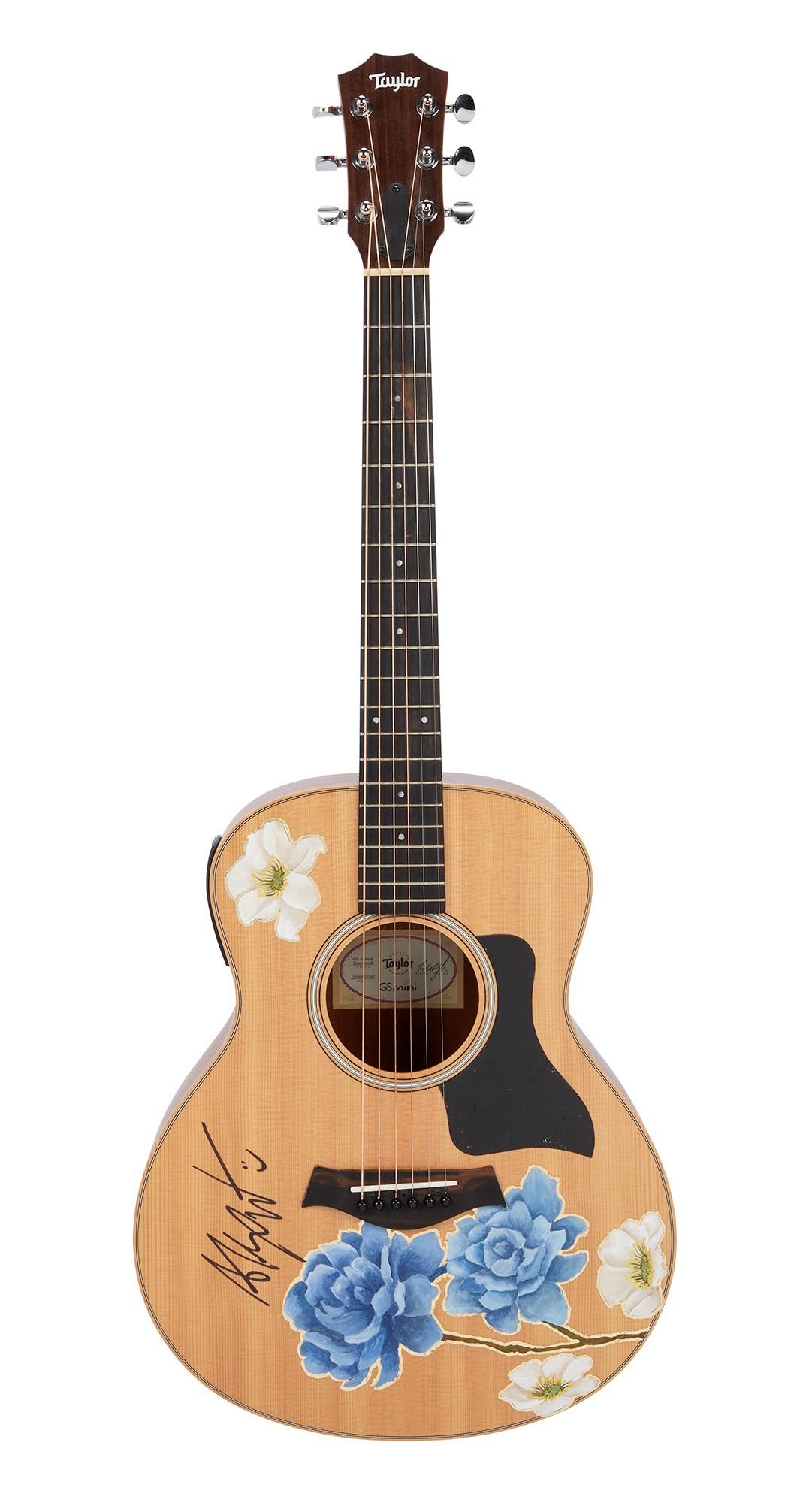 Alex Warren | Signed and Hand-Painted Taylor GS Mini Acoustic Guitar by his wife, Kouvr Annon A light wood Taylor acoustic guitar decorated with blue and white flowers and a signature on the body.