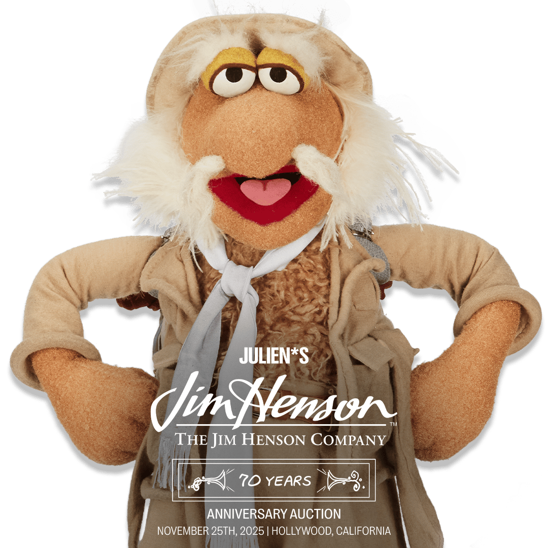 A friendly, white-bearded Jim Henson puppet wearing a tan explorer hat, advertising 'Julien's Jim Henson 70 Years Anniversary Auction, November 25th, 2025'.