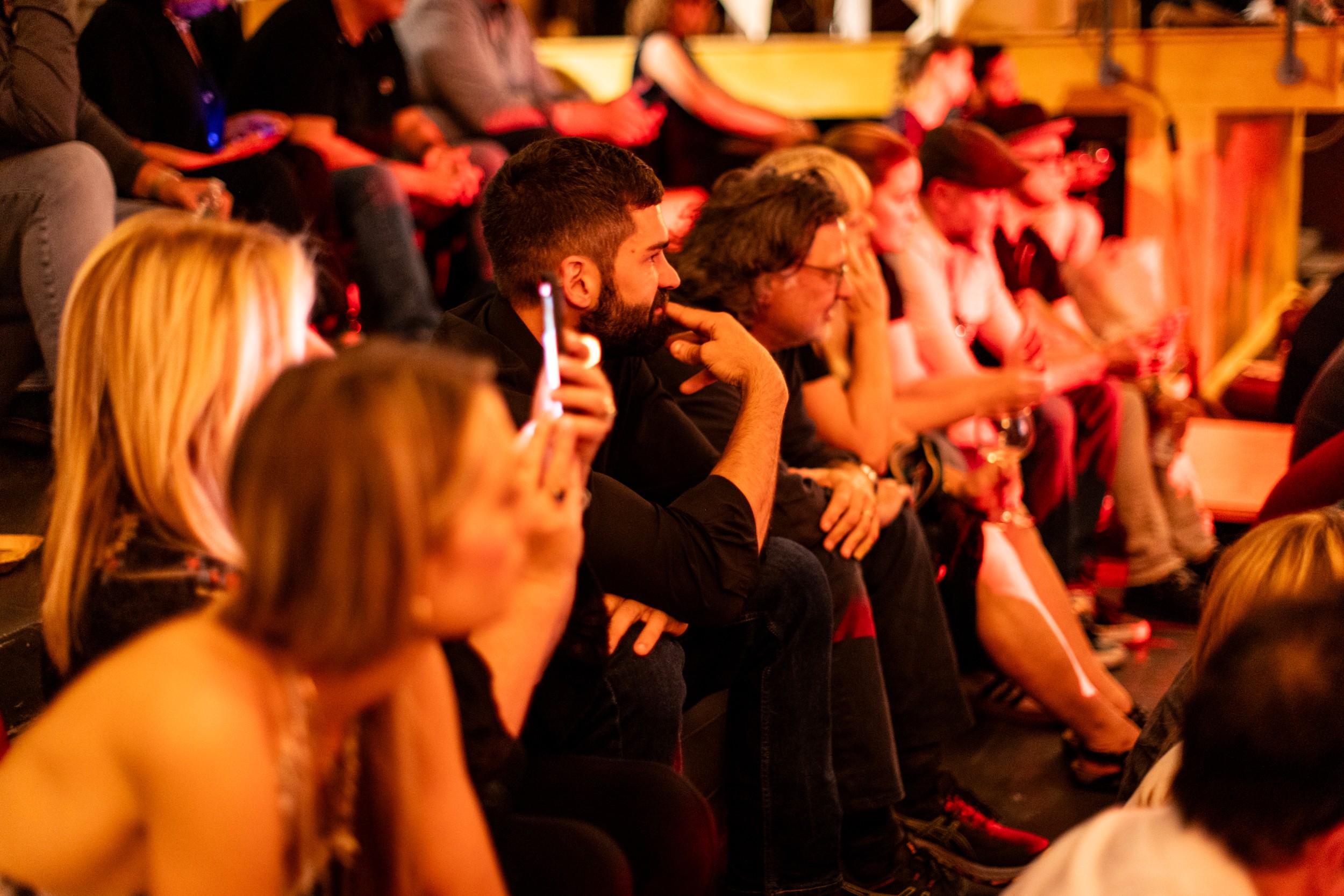a group of people are sitting in a circle watching a show .