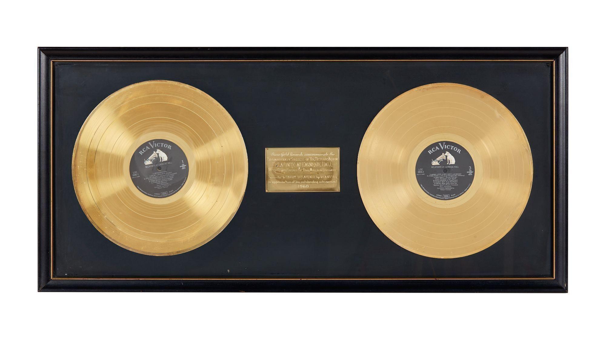 two gold records in a black frame on a white background .