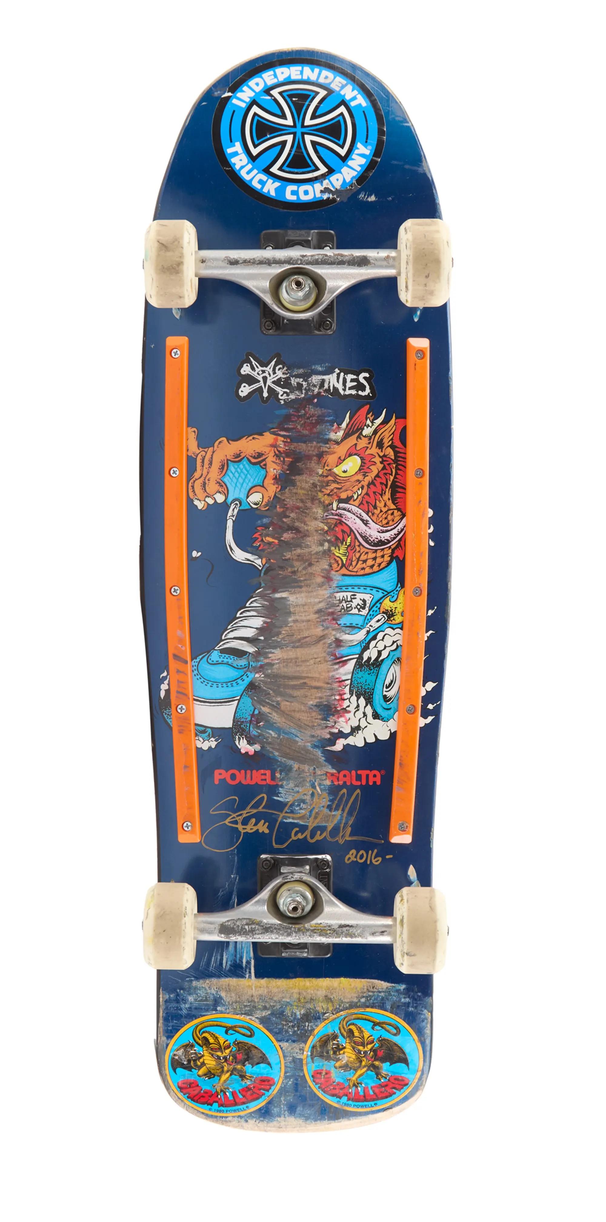 Lot #47. Steve Caballero | Ridden and Signed "Animal Chin" 2016 Quadruple Invert Re-Enactment Skateboard A well-worn blue skateboard featuring a dragon graphic, orange side rails, an Independent Truck Company sticker, and a Steve Caballero signature.