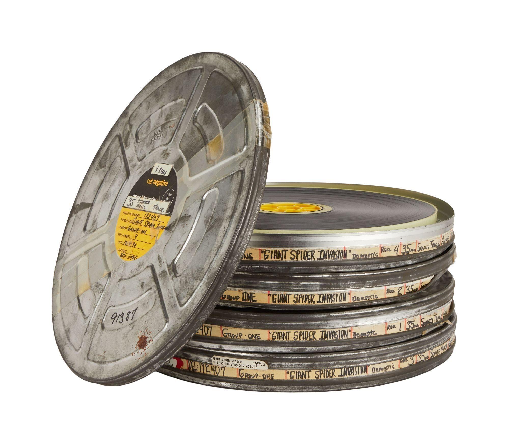 a stack of old film reels with one that says giant spider on it