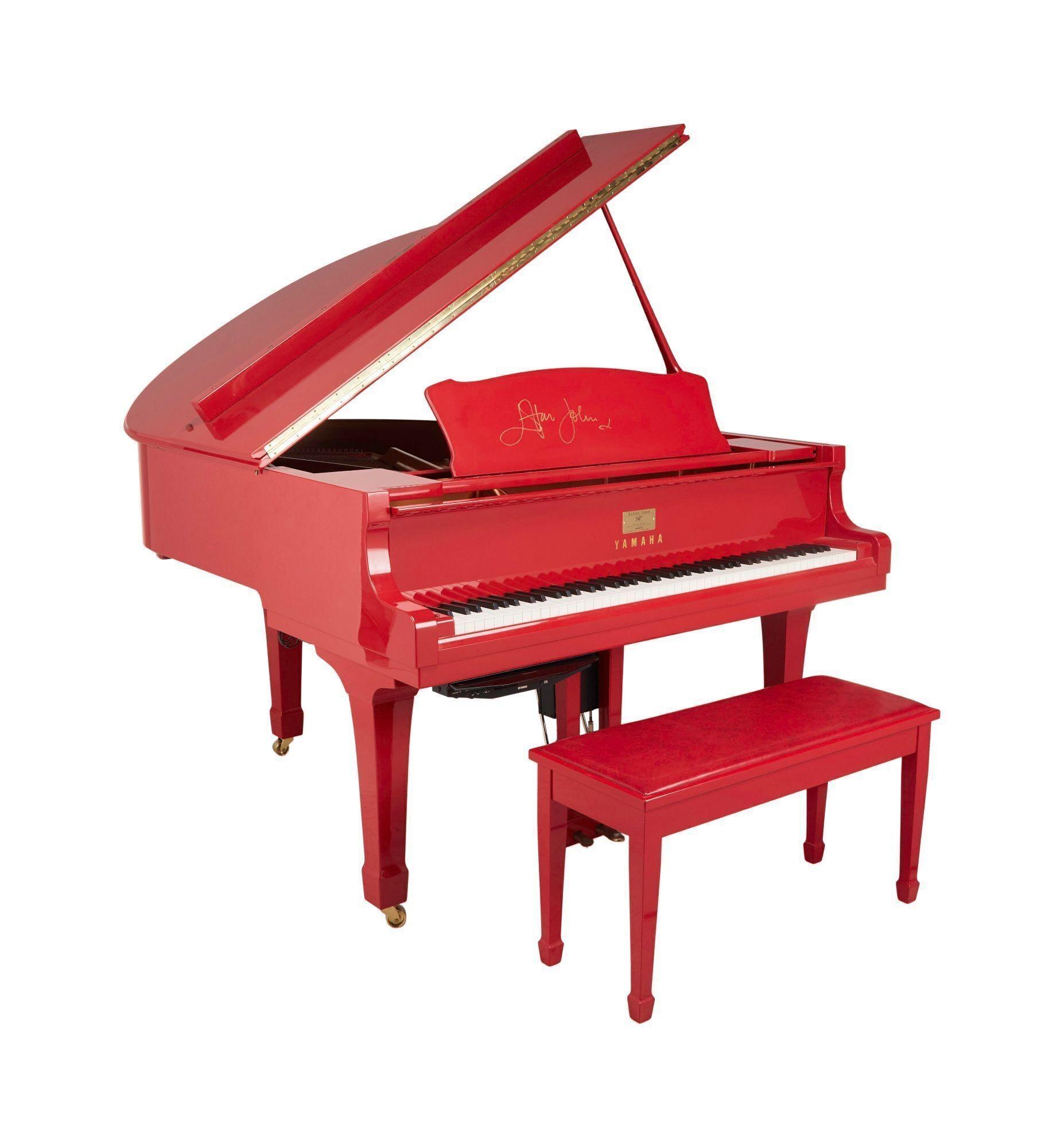 a red yamaha grand piano with a bench next to it