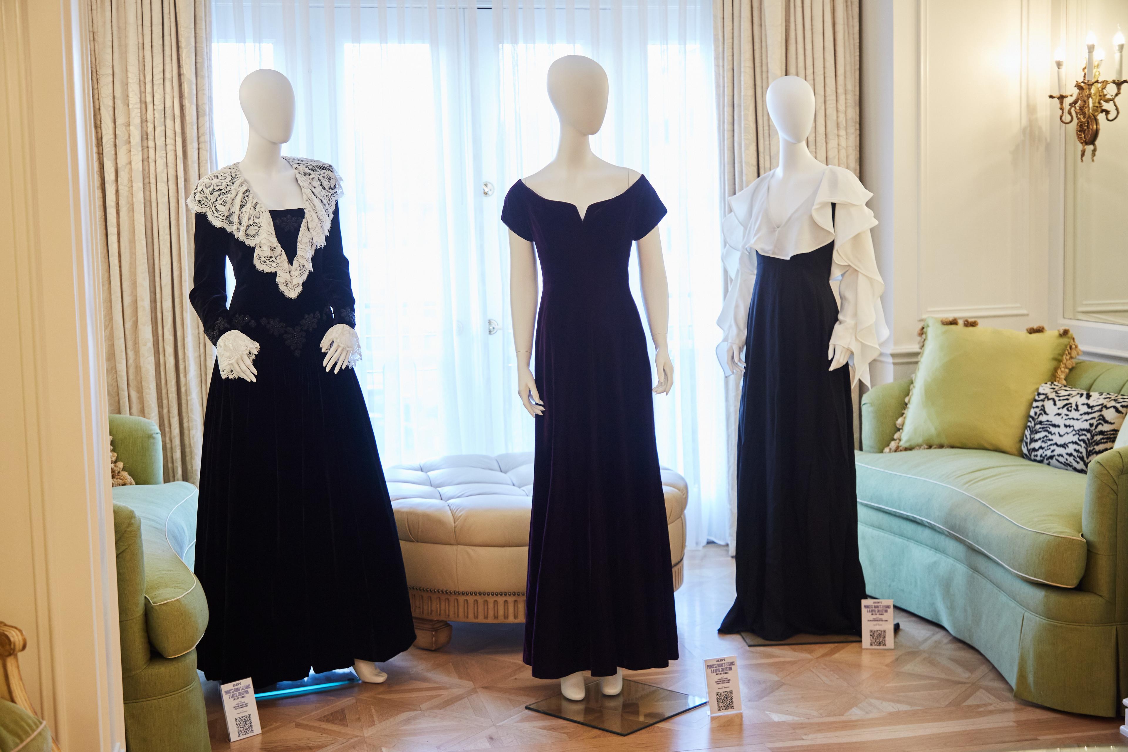 three mannequins wearing black dresses are standing next to each other in a living room .