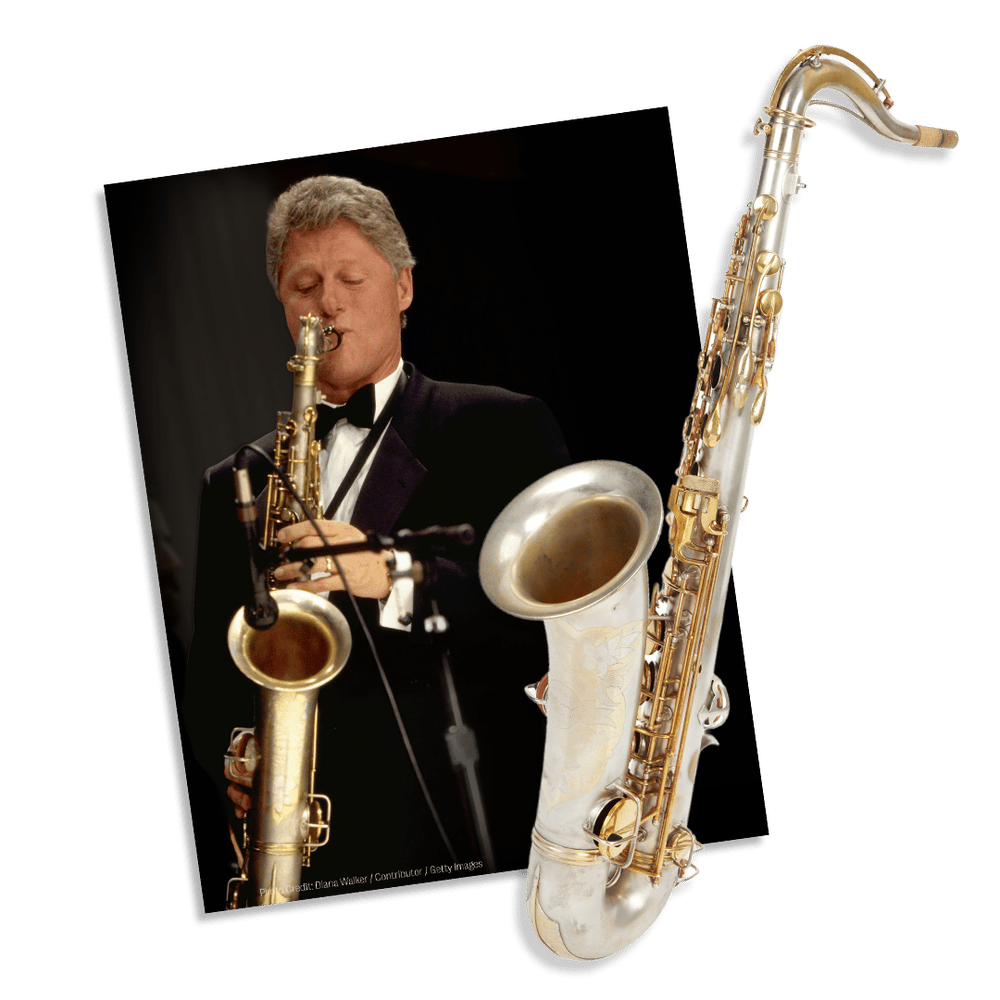 Bill Clinton playing a saxophone in a tuxedo, next to another saxophone.