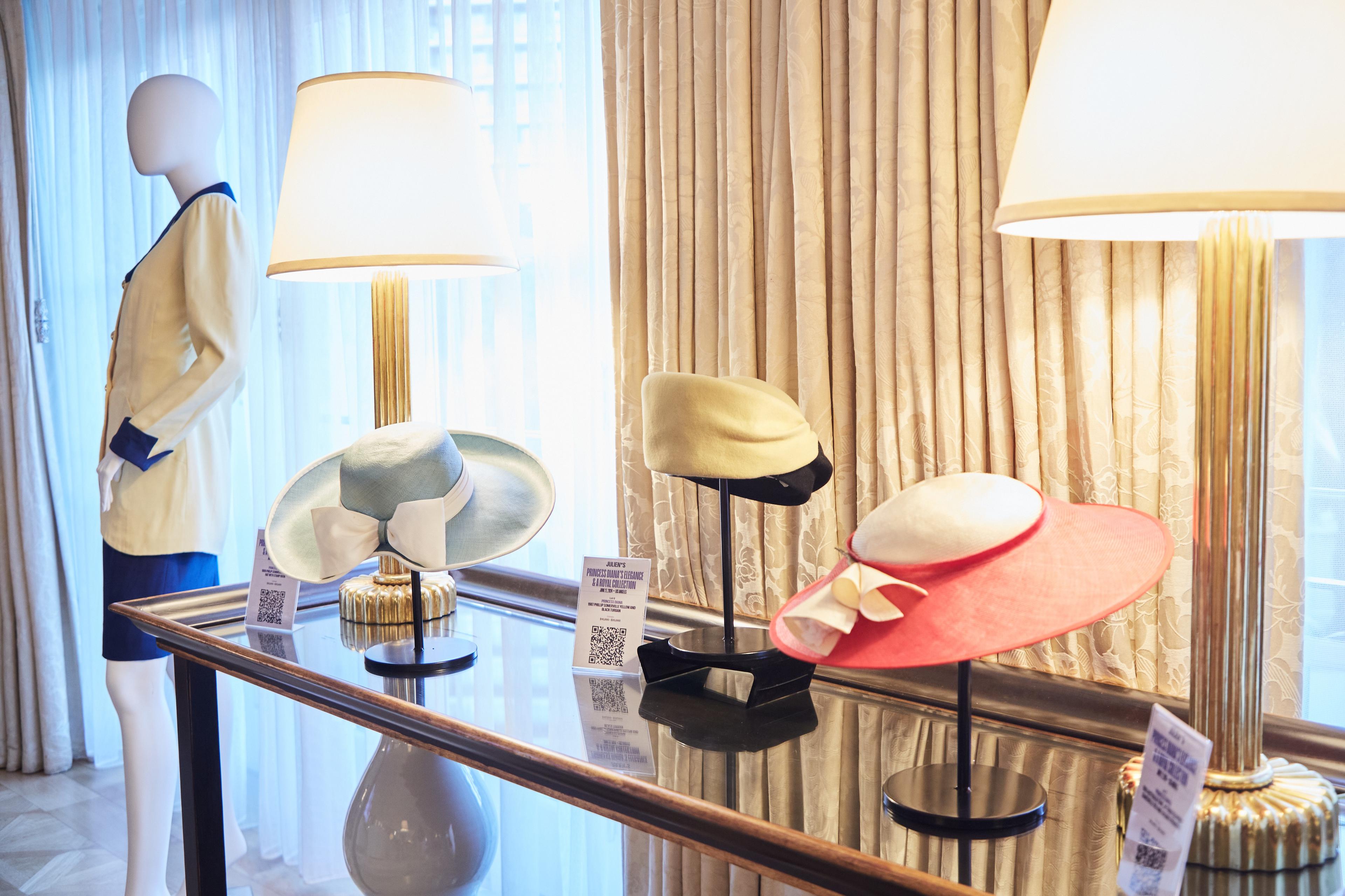 a table with three hats on it and a mannequin in the background .