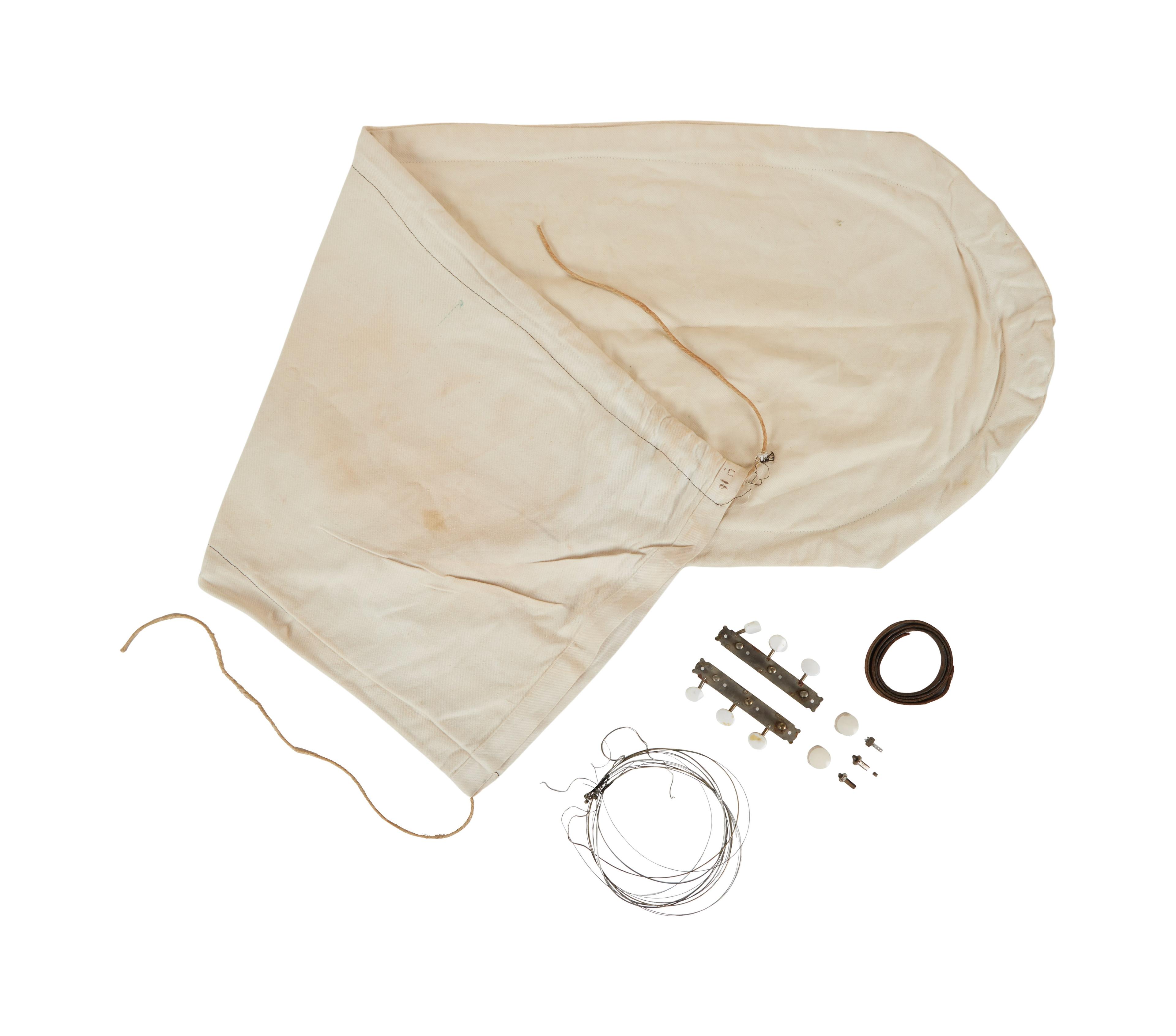 a white cloth bag with a string , buttons , and other items on a white background .