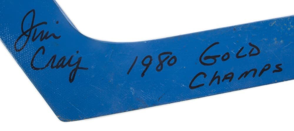 Blue hockey stick blade signed by Jim Craig with "1980 Gold Champs" written on it.