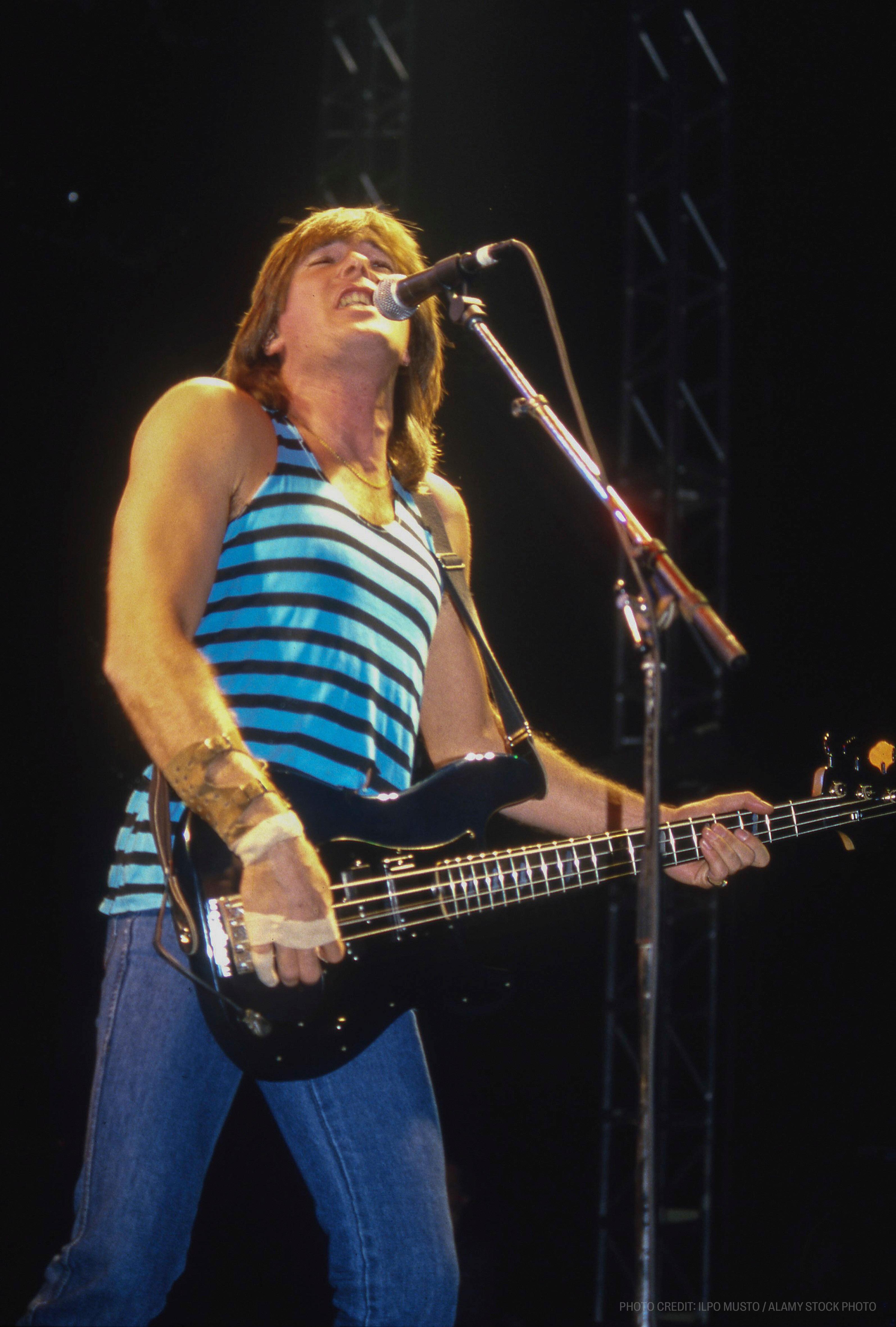 a man singing into a microphone while playing a bass guitar