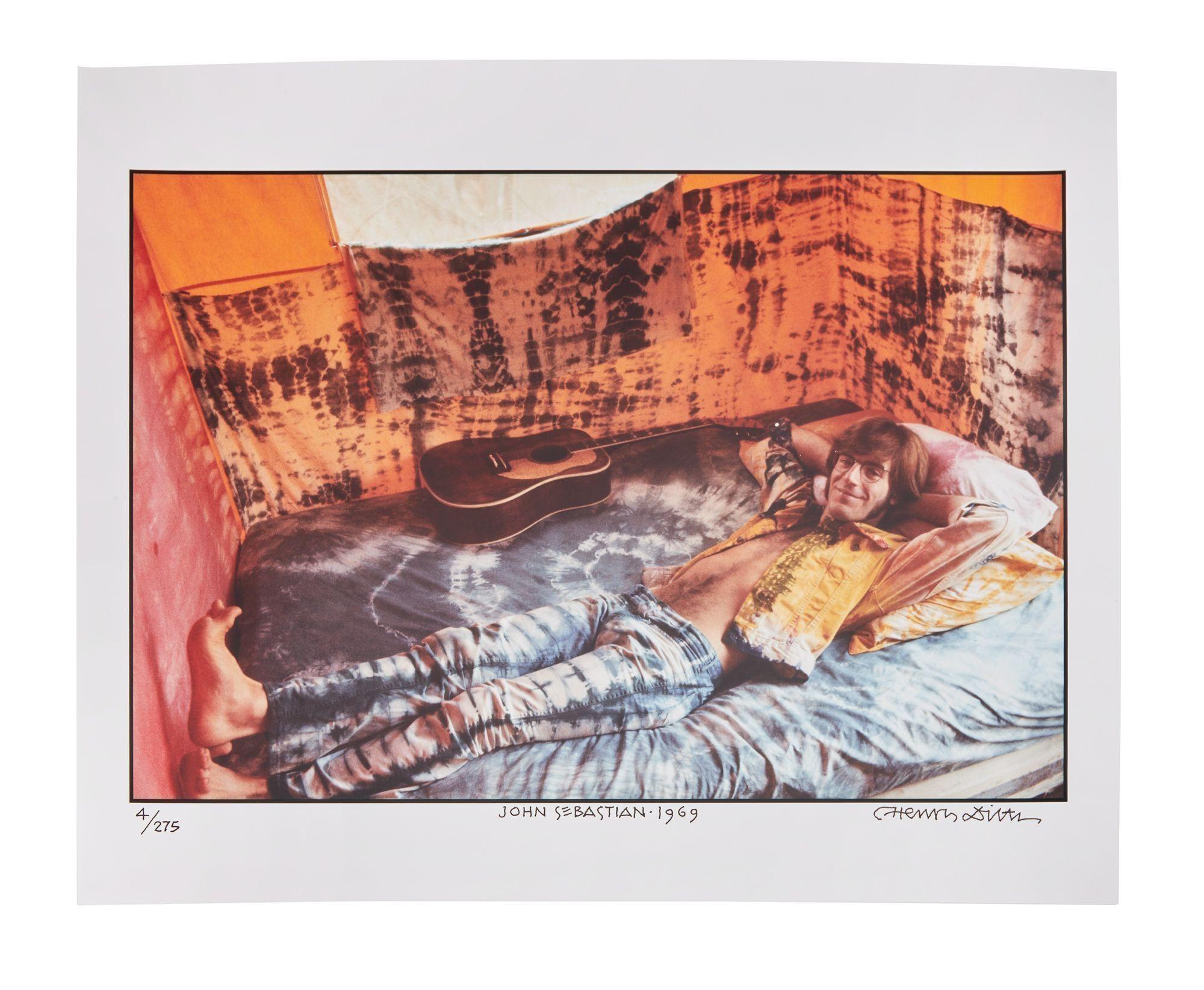 a man is laying on a bed with a guitar .