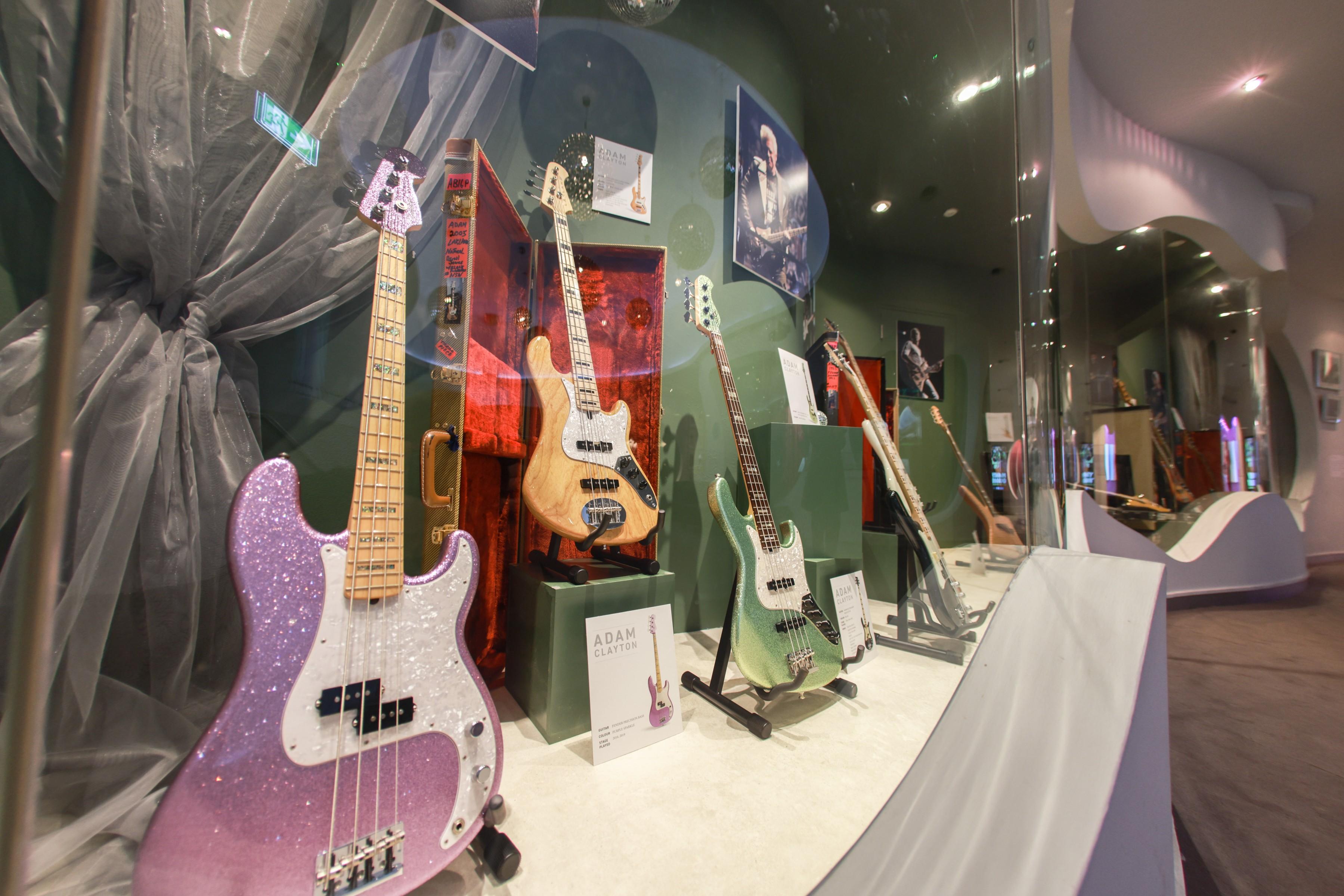 three guitars pink beige and green are displayed behind glass at the museum of style icons