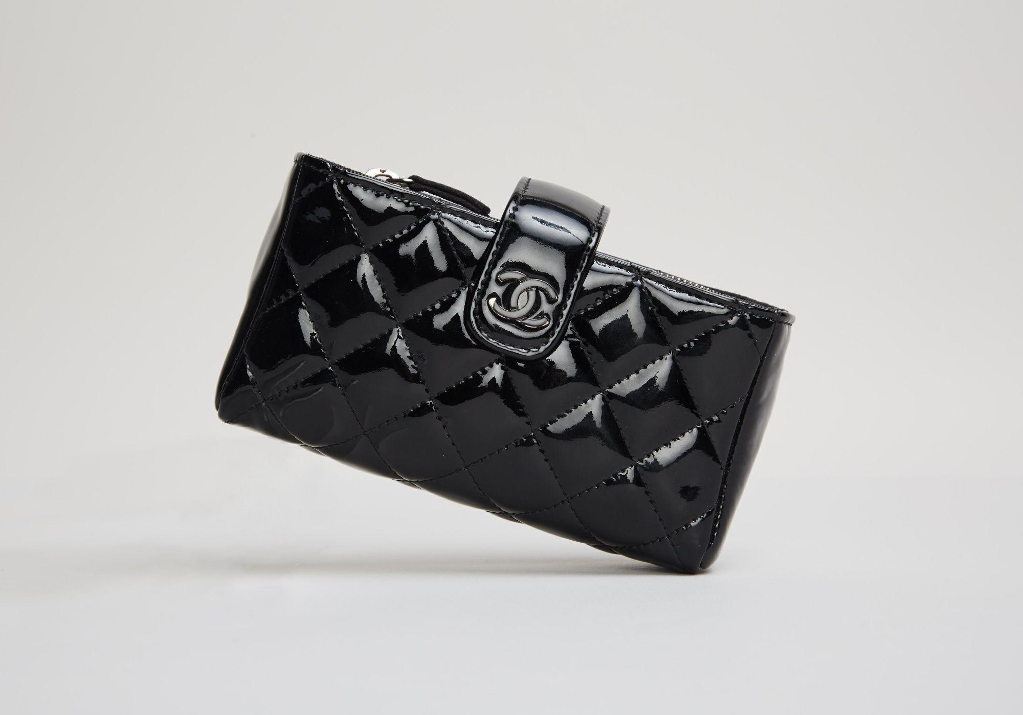 a black chanel wallet is sitting on a white surface .