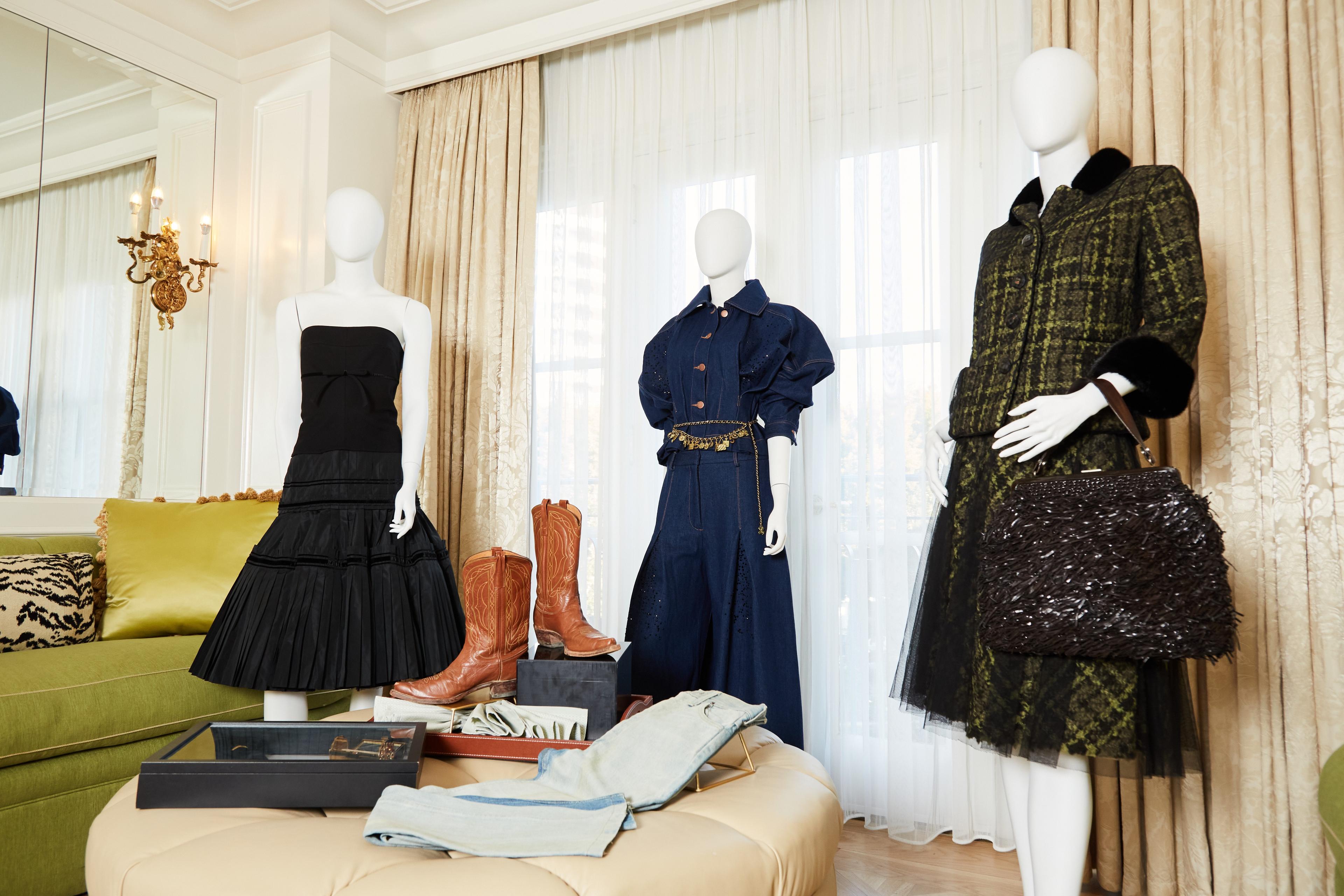 three mannequins are standing next to each other in a room with clothes on display .