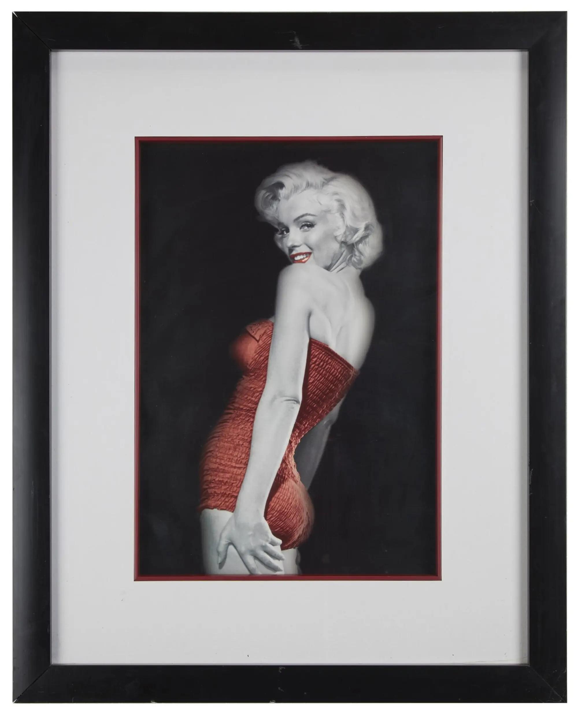 Lot #129. Marilyn Monroe | 1953/1990s Colorized Poster by Bert Reisfeld Framed partially cLot #129 Marilyn Monroe 1953/1990s Colorized Poster by Bert Reisfeldolorized photo of Marilyn Monroe in a red strapless swimsuit, smiling over her shoulder.