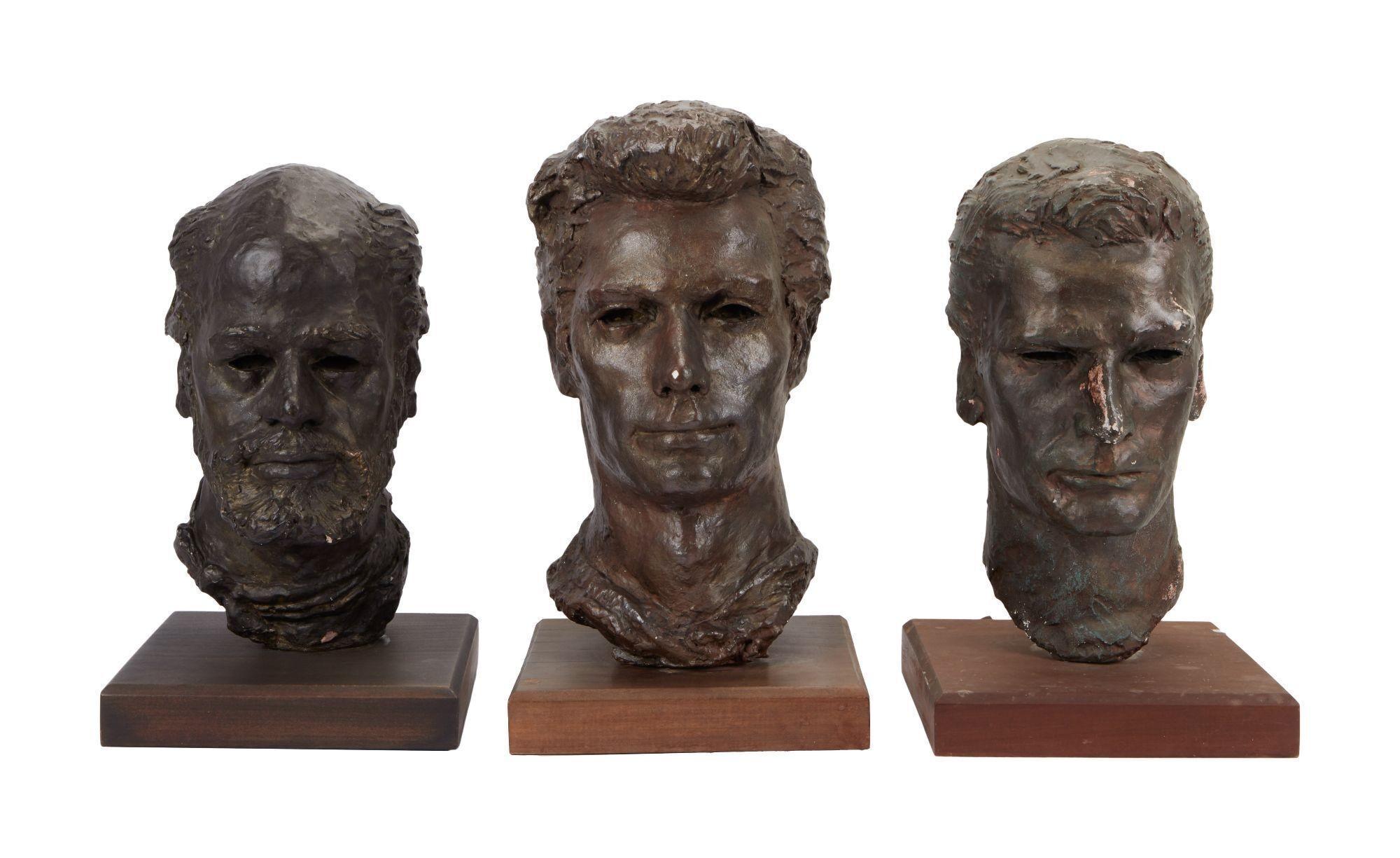 three bronze sculptures of men 's heads are sitting on wooden bases .