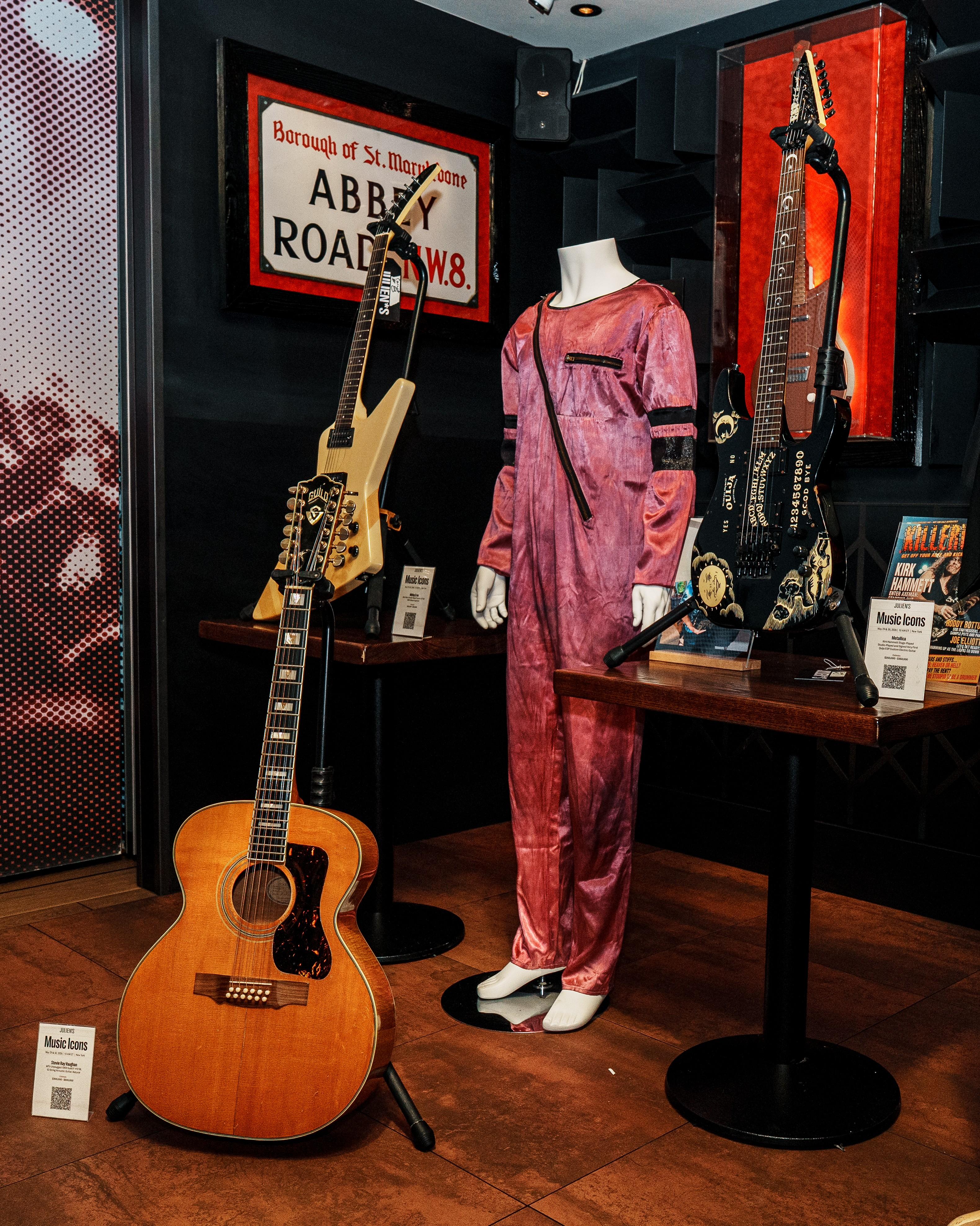 Ace Frehley/Arthur Kane Stage Worn Jumpsuit - Purple Velour One Piece Jumpsuit with Asymmetric Chest Zipper and Black Armbands. Jumpsuit was originally Silver/White, worn on stage by Arthur Kane of The New York Dolls. Kane gave the Jumpsuit to Frehley, who dyed it purple before wearing it on stage. guitars and jumpsuit with sign that reads abbey road
