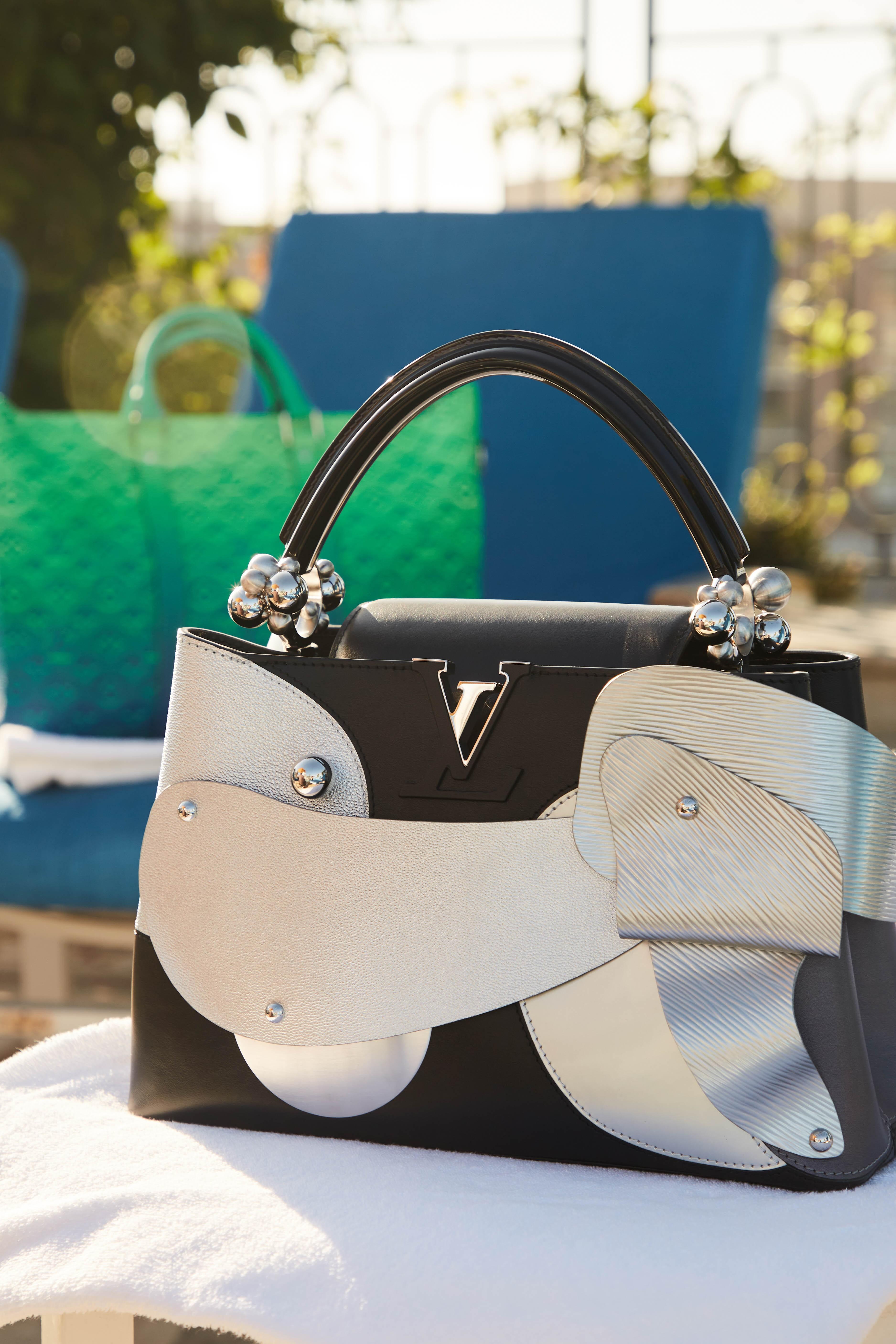 Lot 2, Louis Vuitton Puppy Purse and Lot 1, Louis Vuitton Green Luggage a black and white purse with the letter v on it