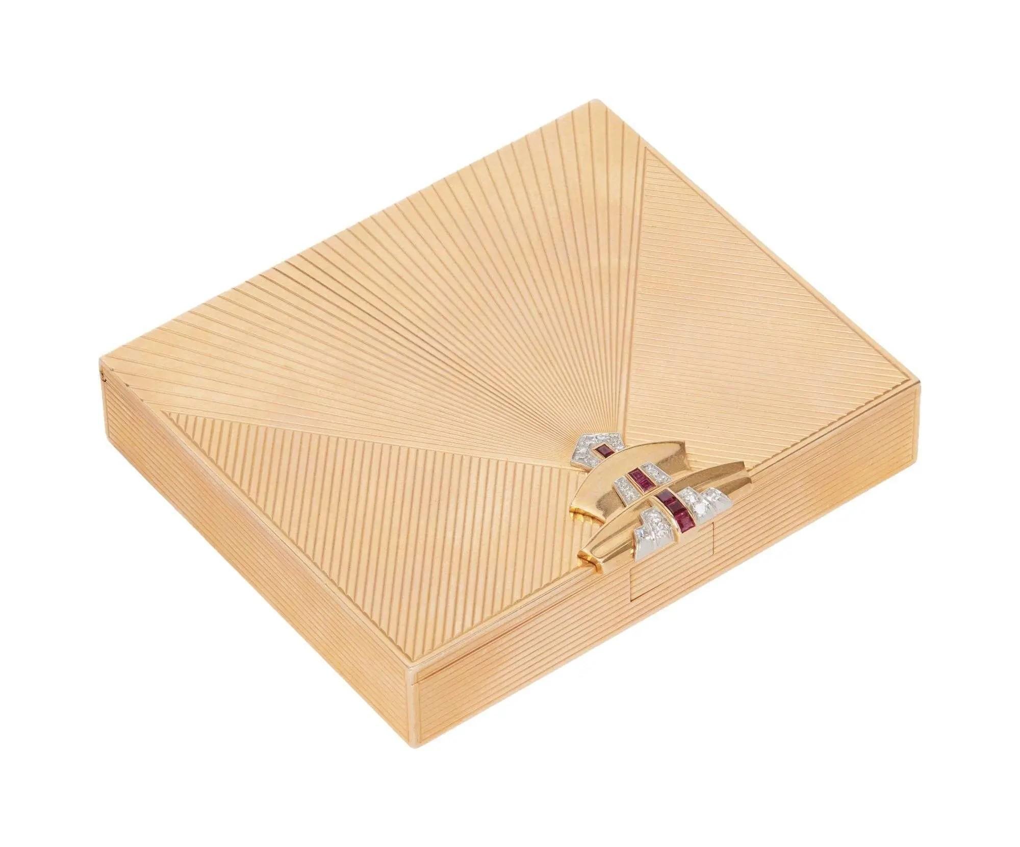 Lot #132. Whoopi Goldberg | Late Art Deco 14k Yellow Gold Synthetic Ruby and Diamond Cigarette Case Art Deco gold compact with radiating pattern and ruby and diamond clasp.