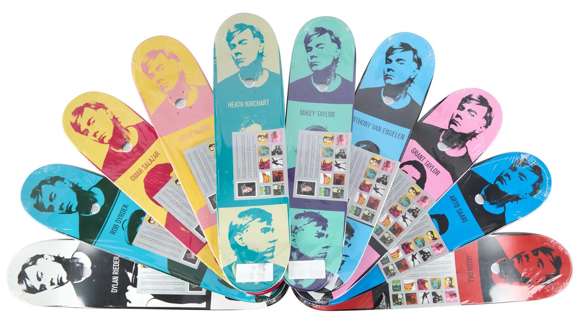 A fan of brightly colored skateboard decks, each with a pop art portrait and wrapped in plastic.