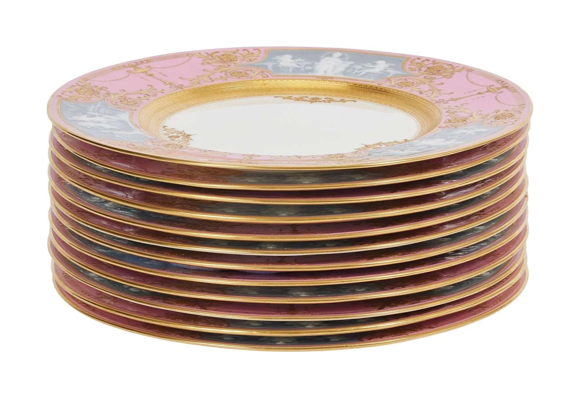 Stack of eleven decorative plates with pink, blue-gray, and gold classical designs.