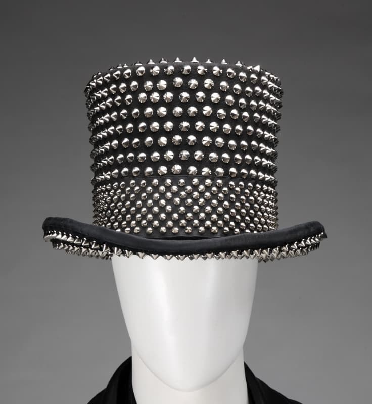 Black top hat covered in silver studs, on a mannequin.