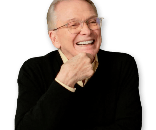 a man wearing glasses and a black sweater is laughing