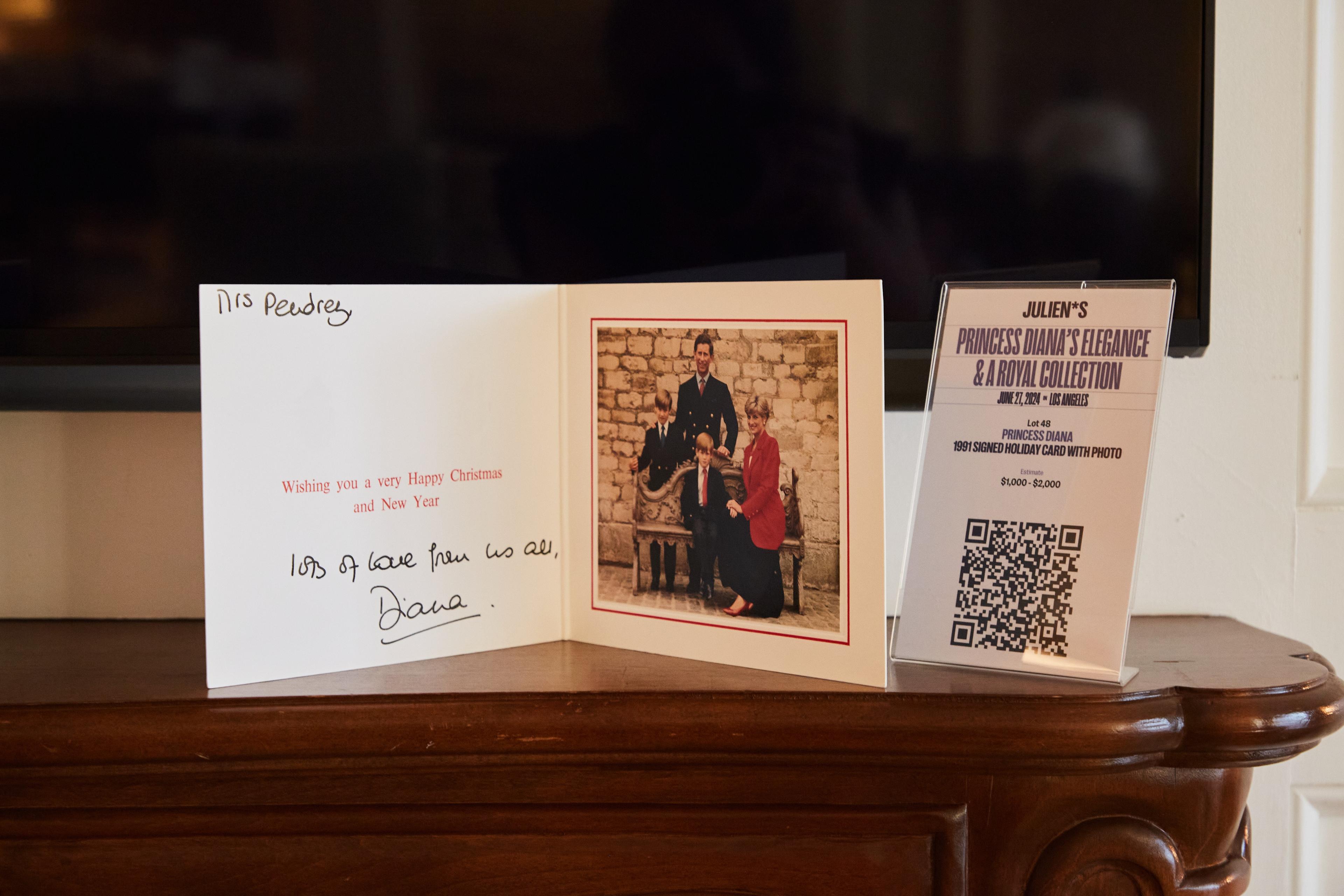a christmas card with a picture of princess diana and her family is on a mantle next to a television .