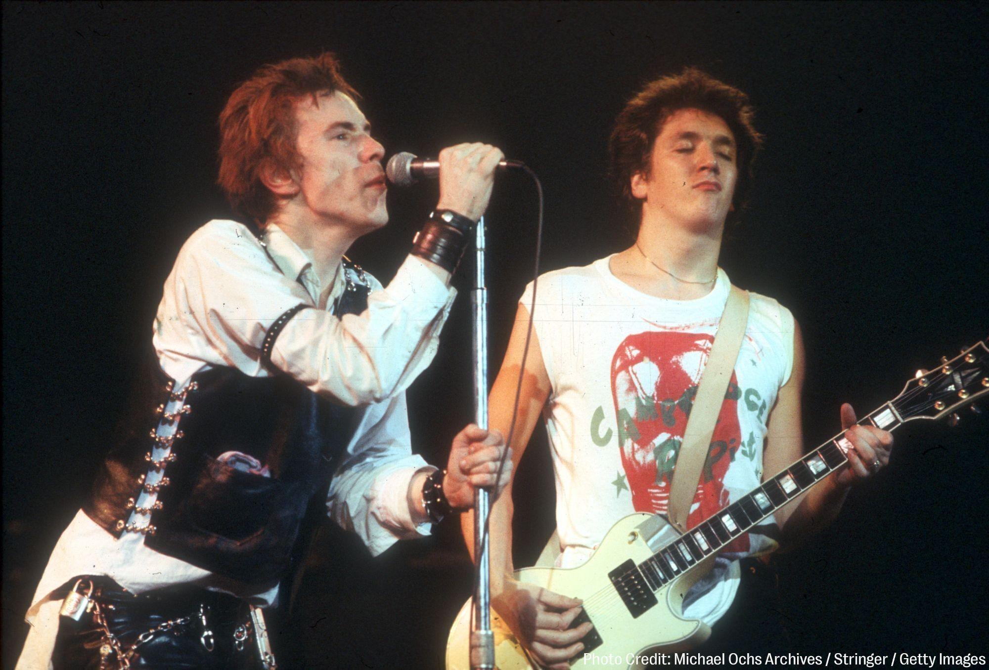 two men are playing guitars and singing into microphones on a stage .