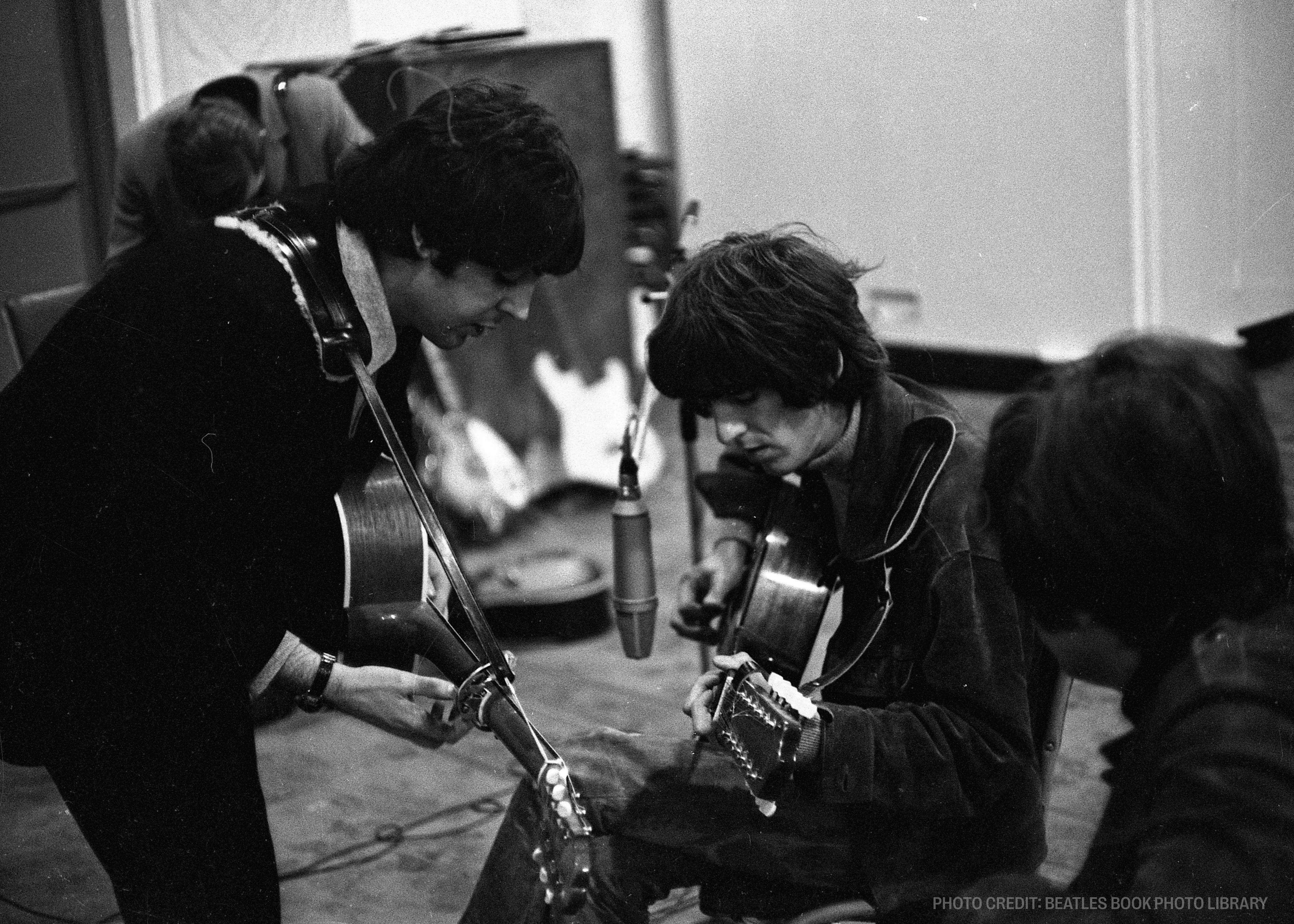 a black and white photo of the beatles in a recording studio .