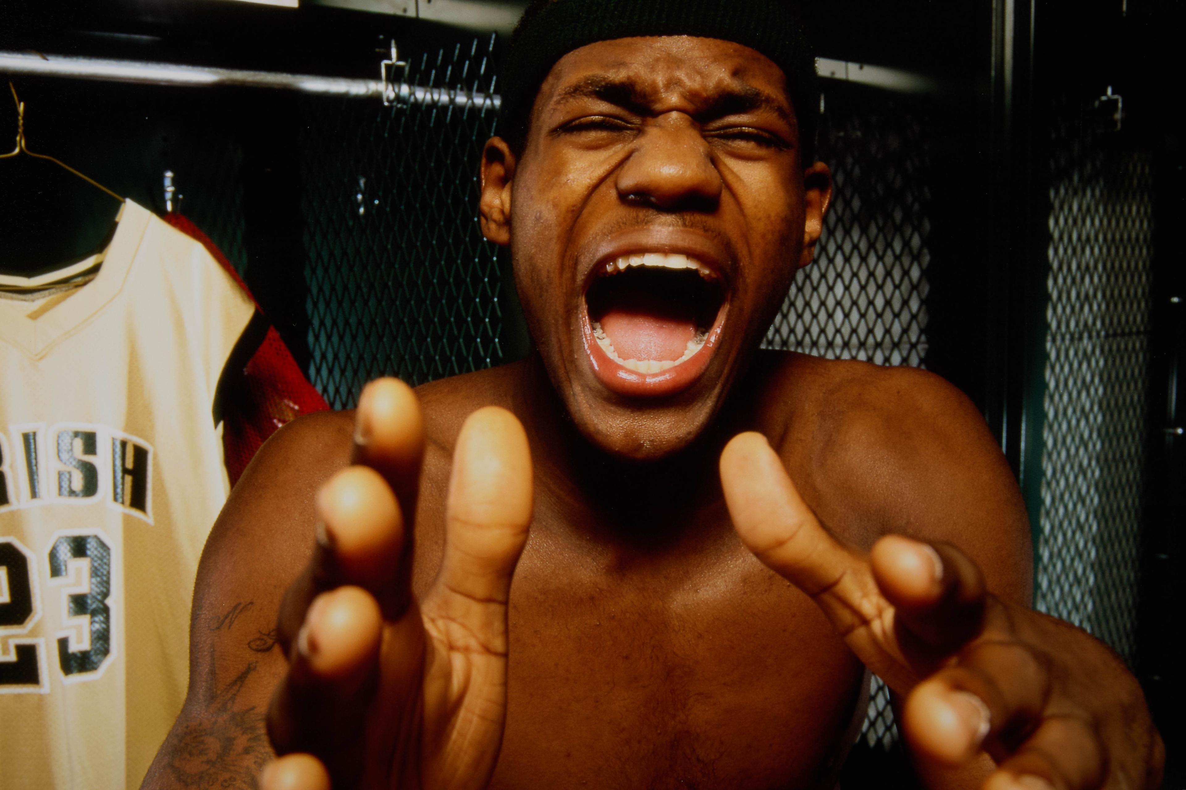 a shirtless basketball player is screaming in a locker room .