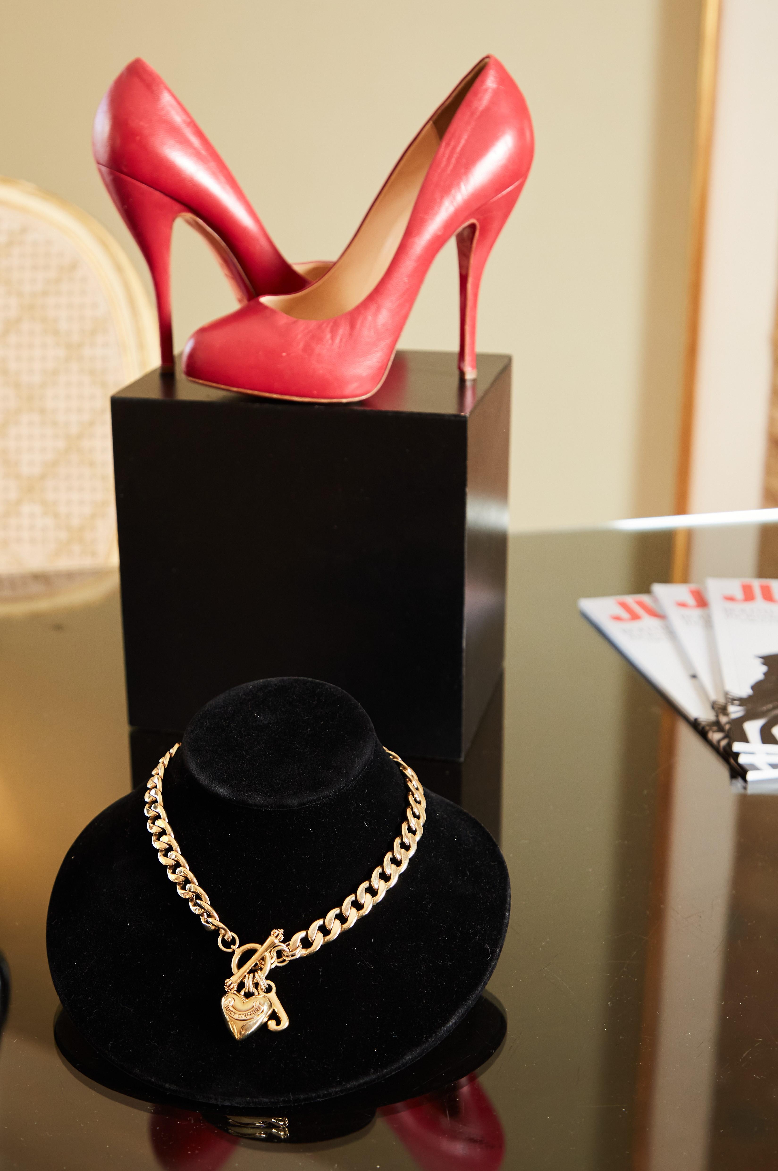 a pair of red high heels and a gold necklace on a table