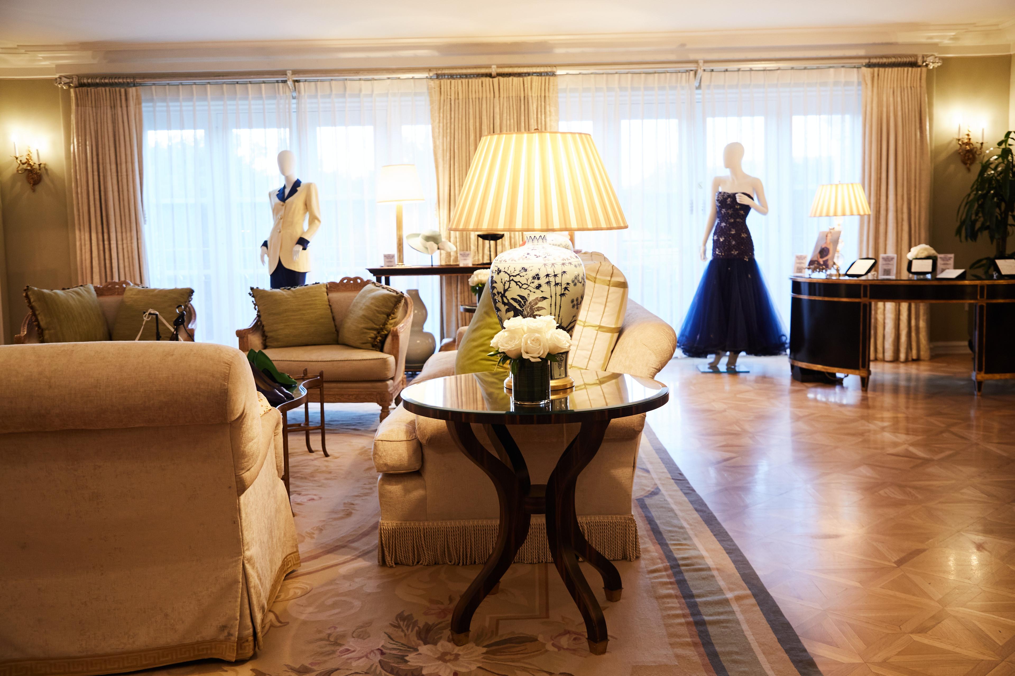 a living room with a couch , chair , table , lamps and mannequins .