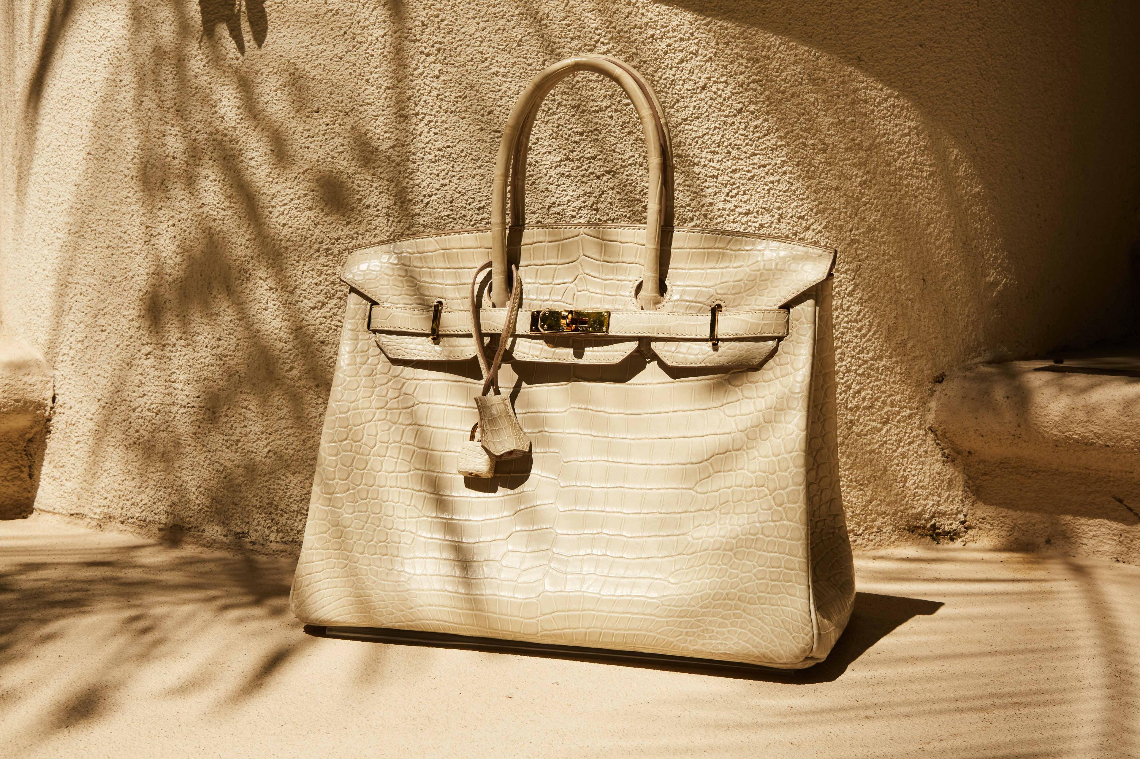 Lot 10, Hermes Birkin a white handbag is sitting on the ground in front of a wall .